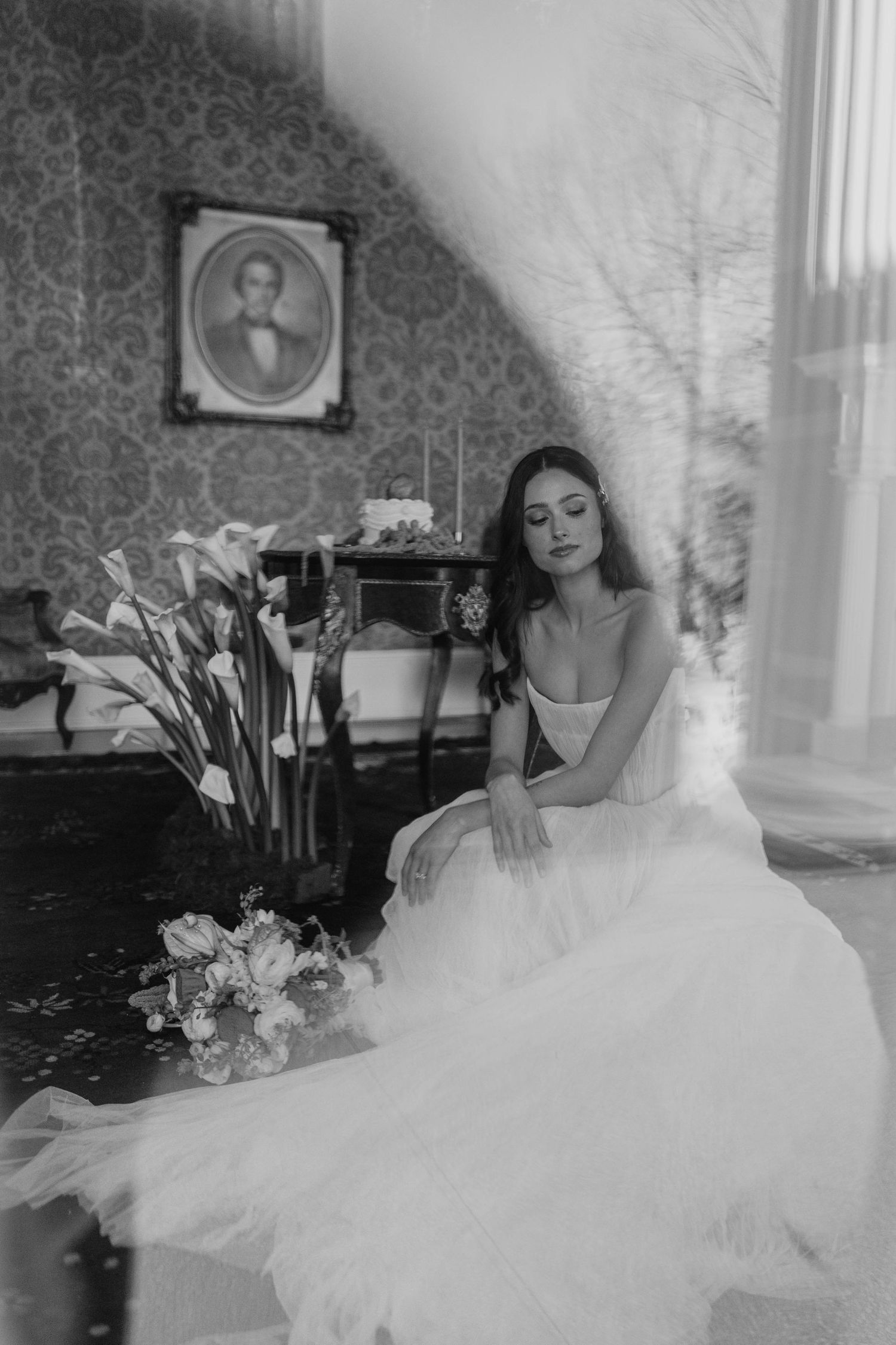 Artistic black and white portrait of a wedding dress against damask wallpaper.