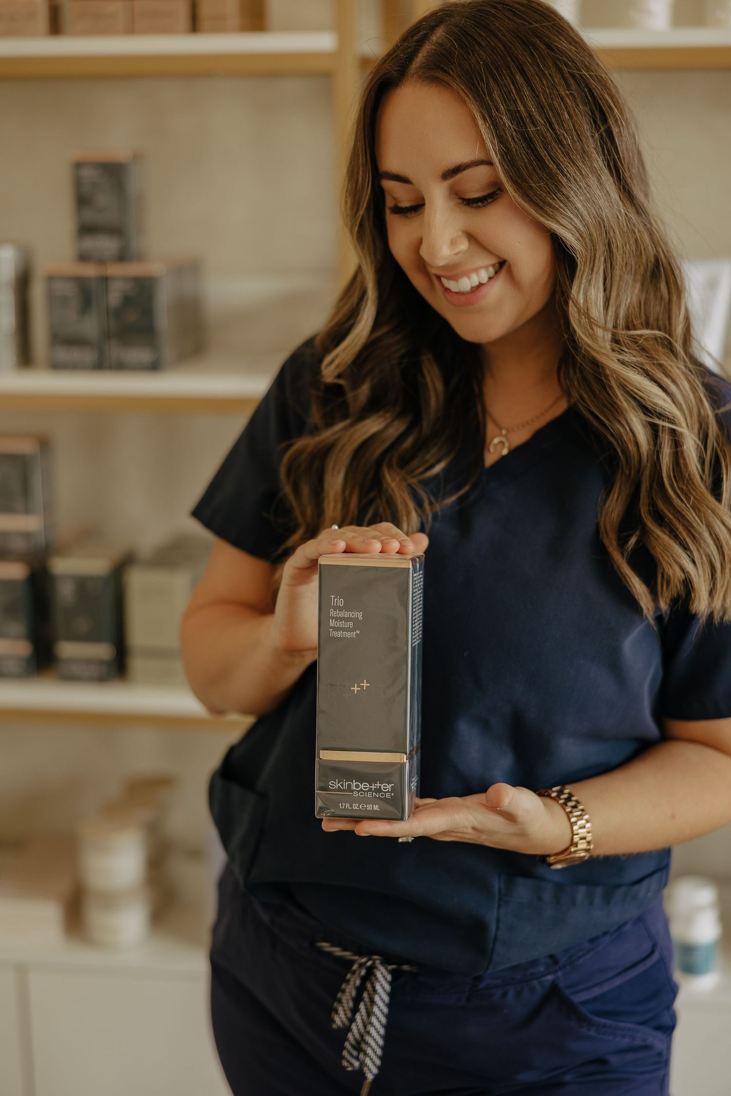 Person in navy scrubs showcasing product packaging with excited expressions.