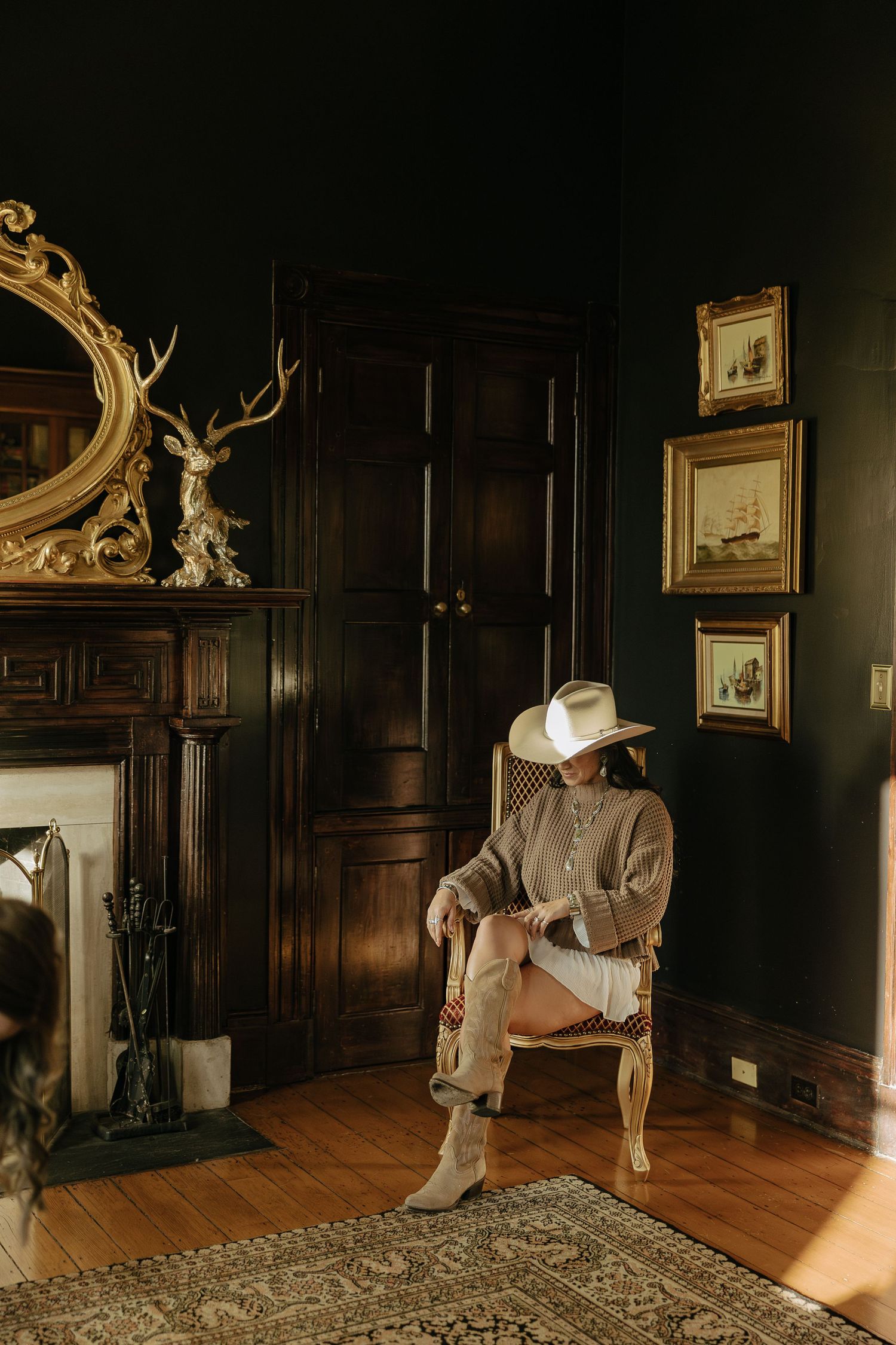 Dramatic indoor portrait session in dark wood-paneled room with golden sunlight streaming in.