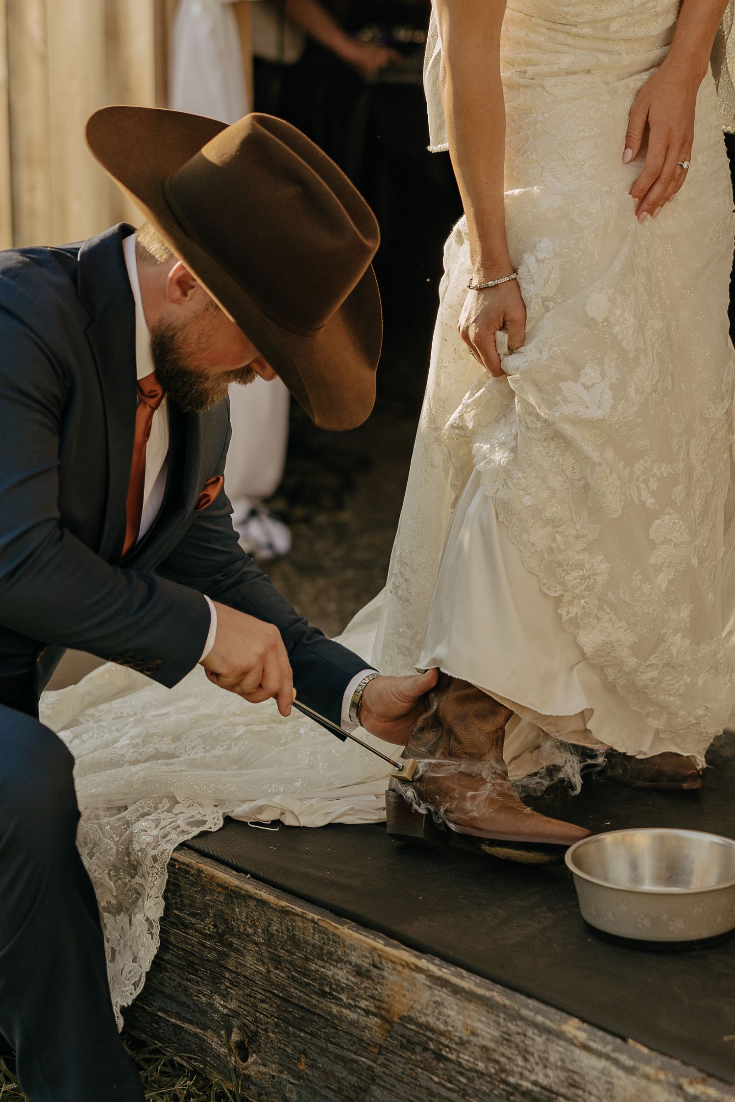 A close-up shot of someone washing feet in a metal basin during a rustic wedding ceremony.