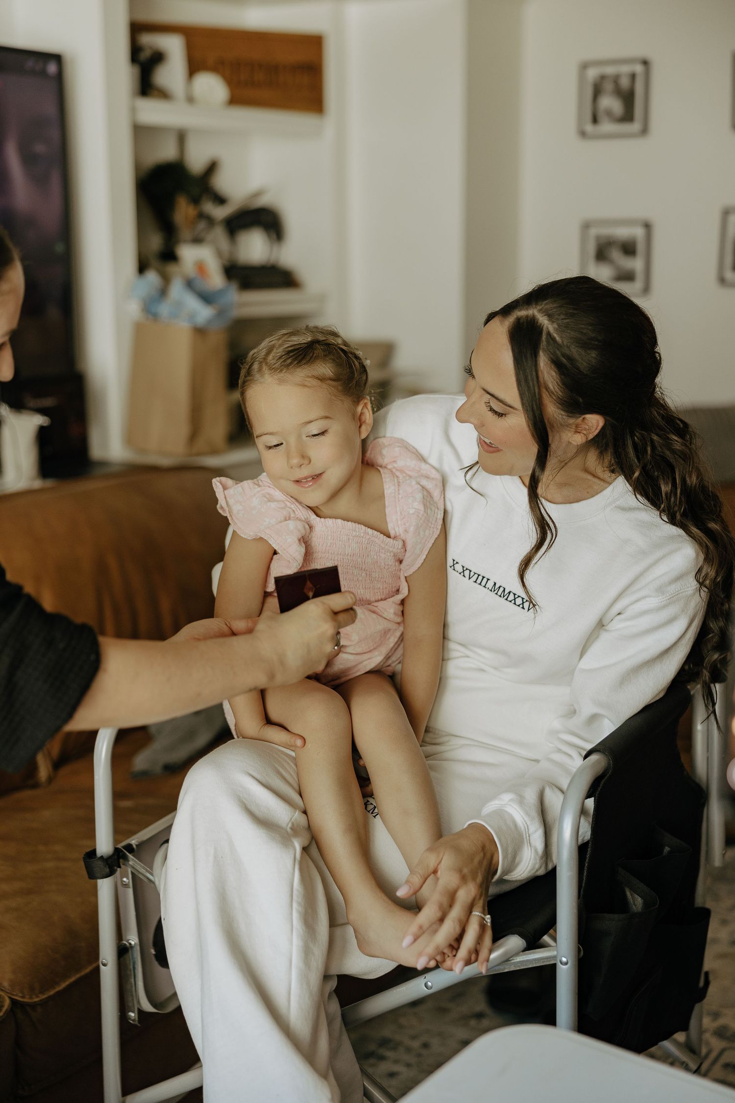 A tender moment between parent and baby in white clothing sitting indoors.