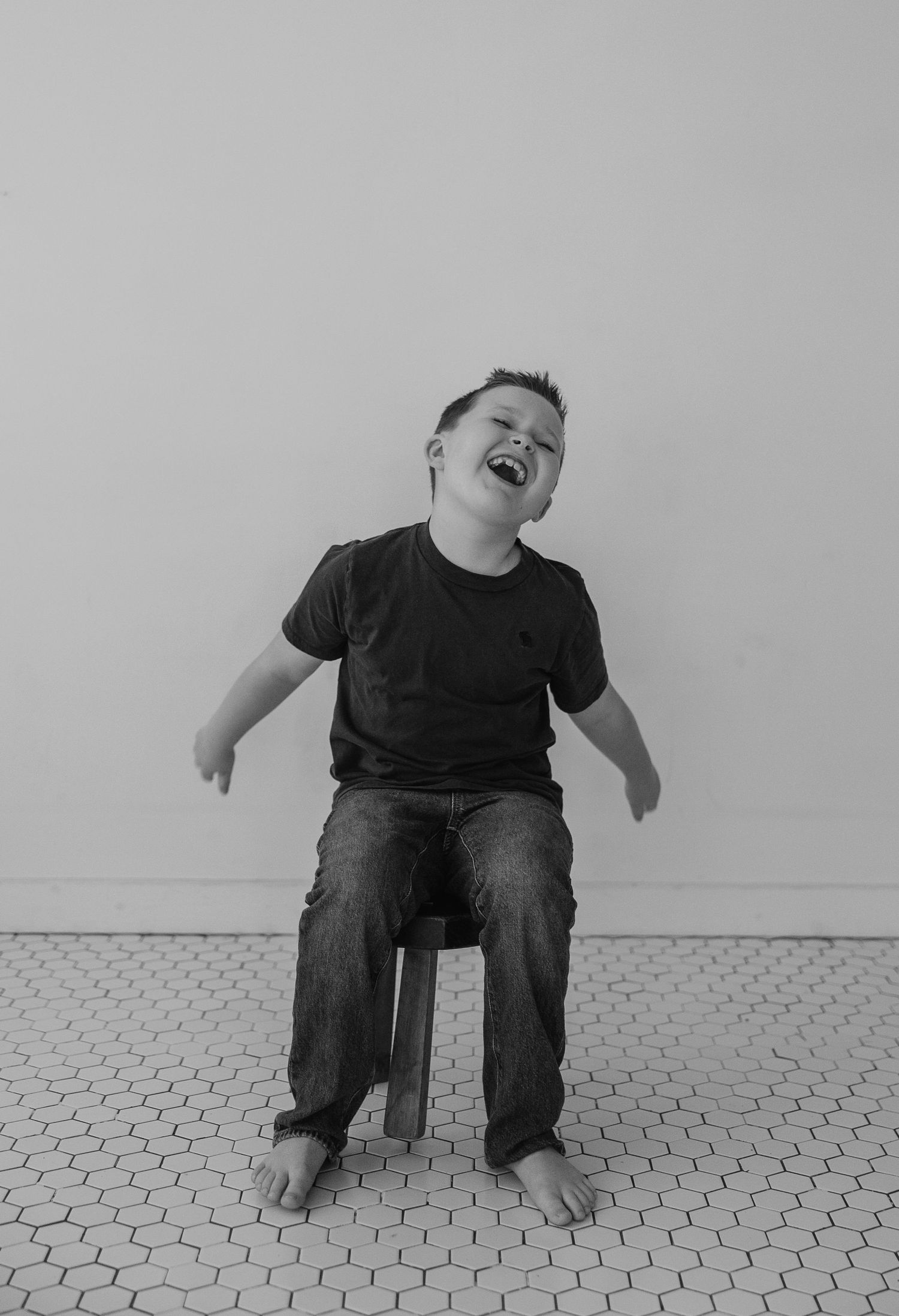 A series of black and white photos showing joyful expressions and laughter while sitting on a small stool.
