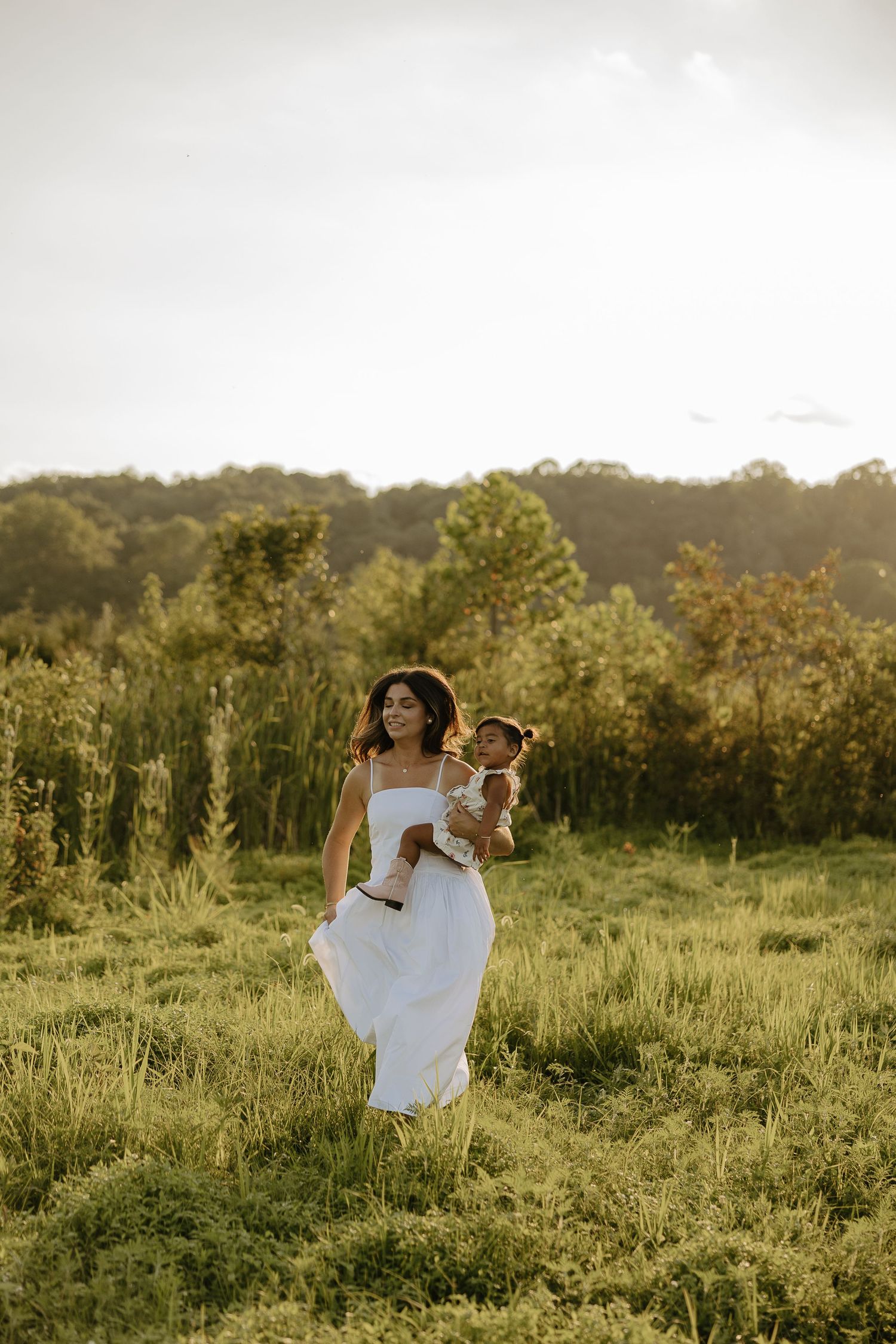 White-dressed figures dancing and twirling in a sunlit meadow.