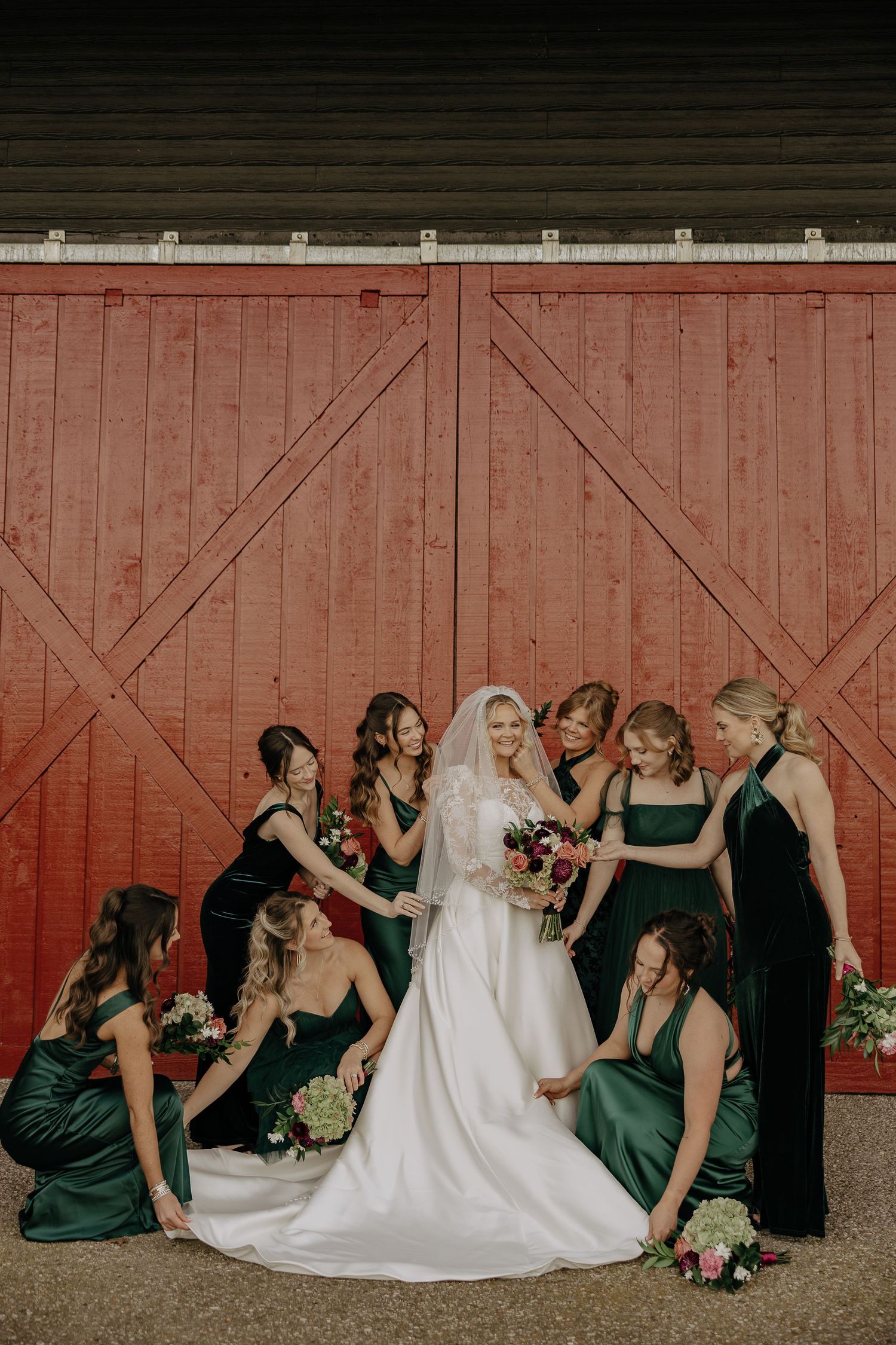 Wedding party in dark dresses poses against red barn wall creating artistic progression of photos.