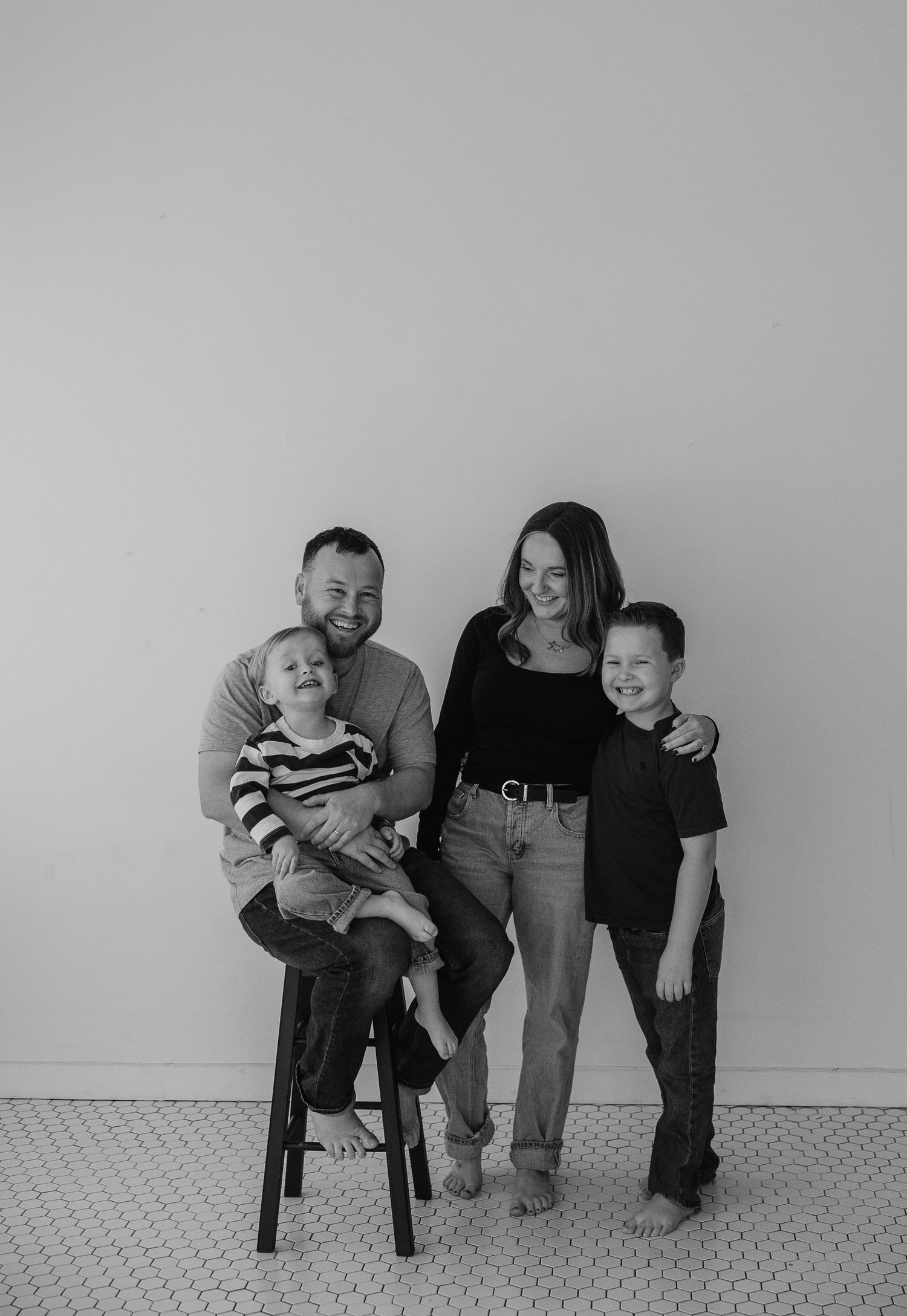 Three black and white candid family photos showing playful moments on chairs against a white wall.