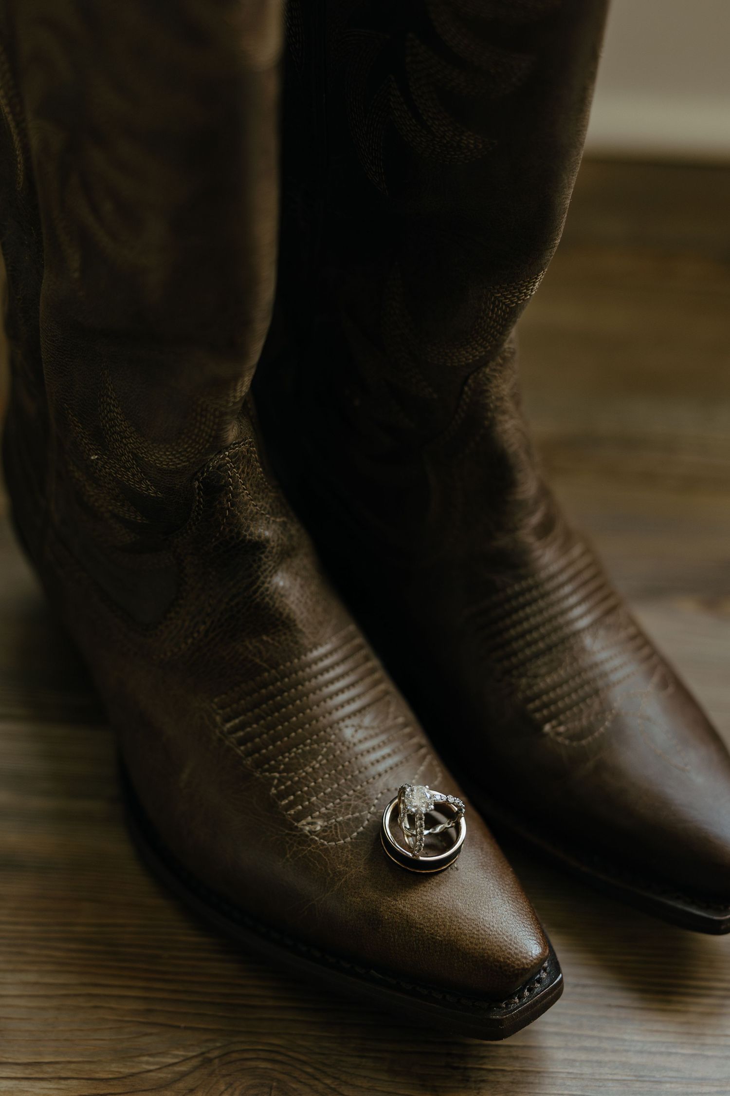 Close-up detail of brown leather cowboy boots on wooden flooring.