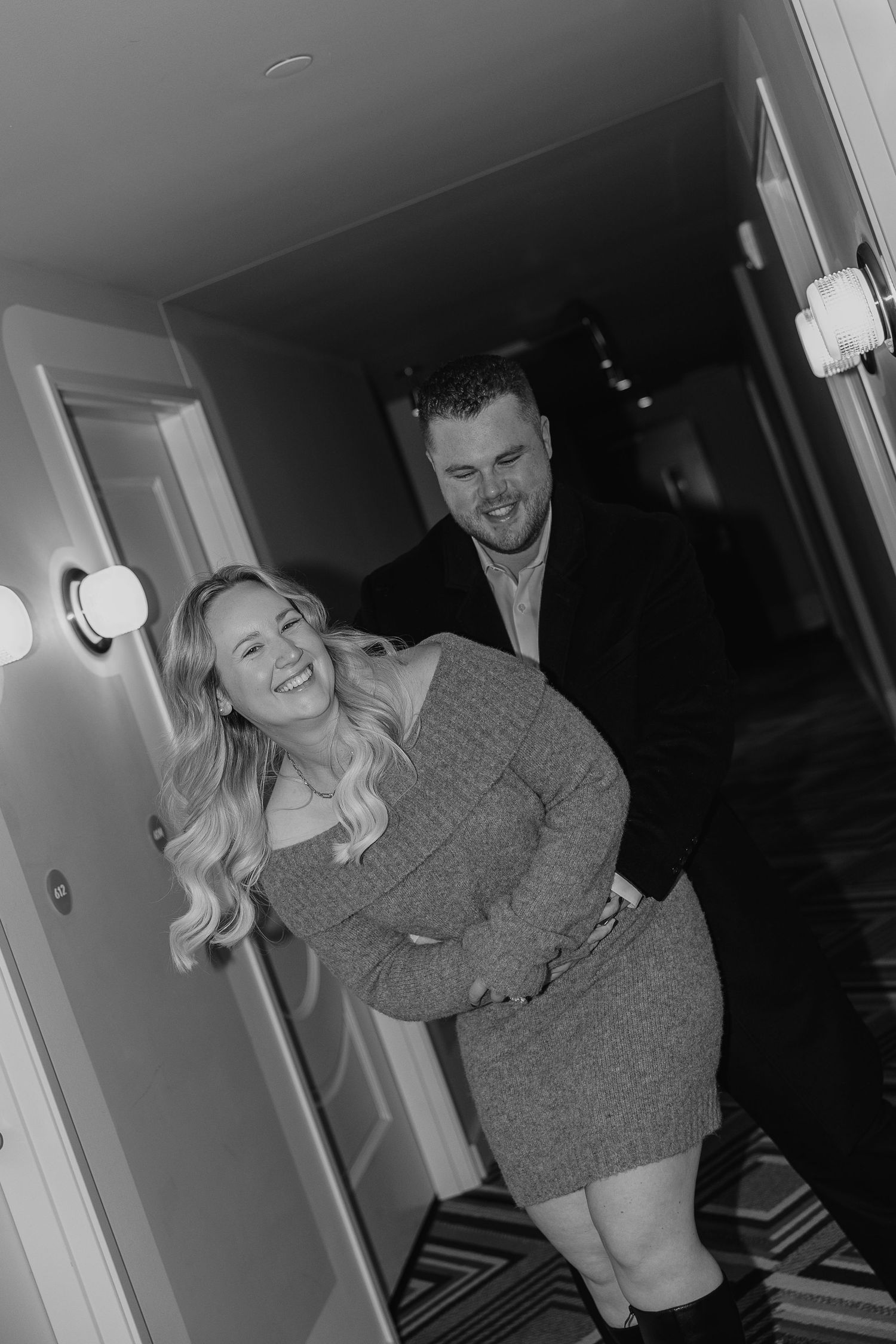 A couple shares intimate moments in a dimly lit hallway.