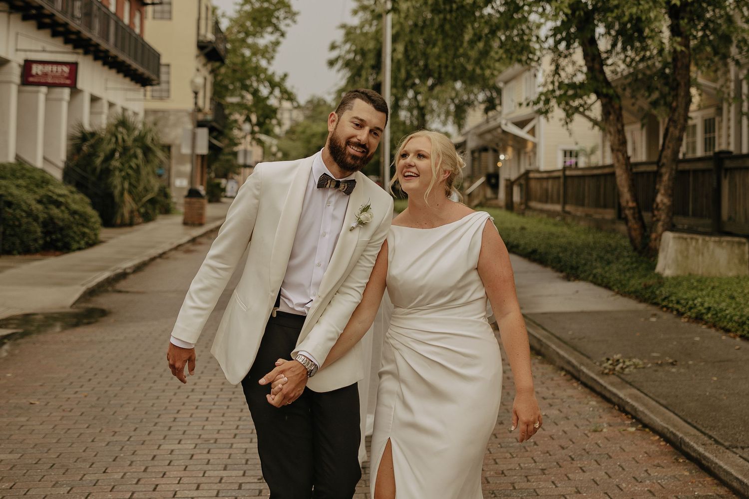 Couple walking and laughing together on a tree-lined street.