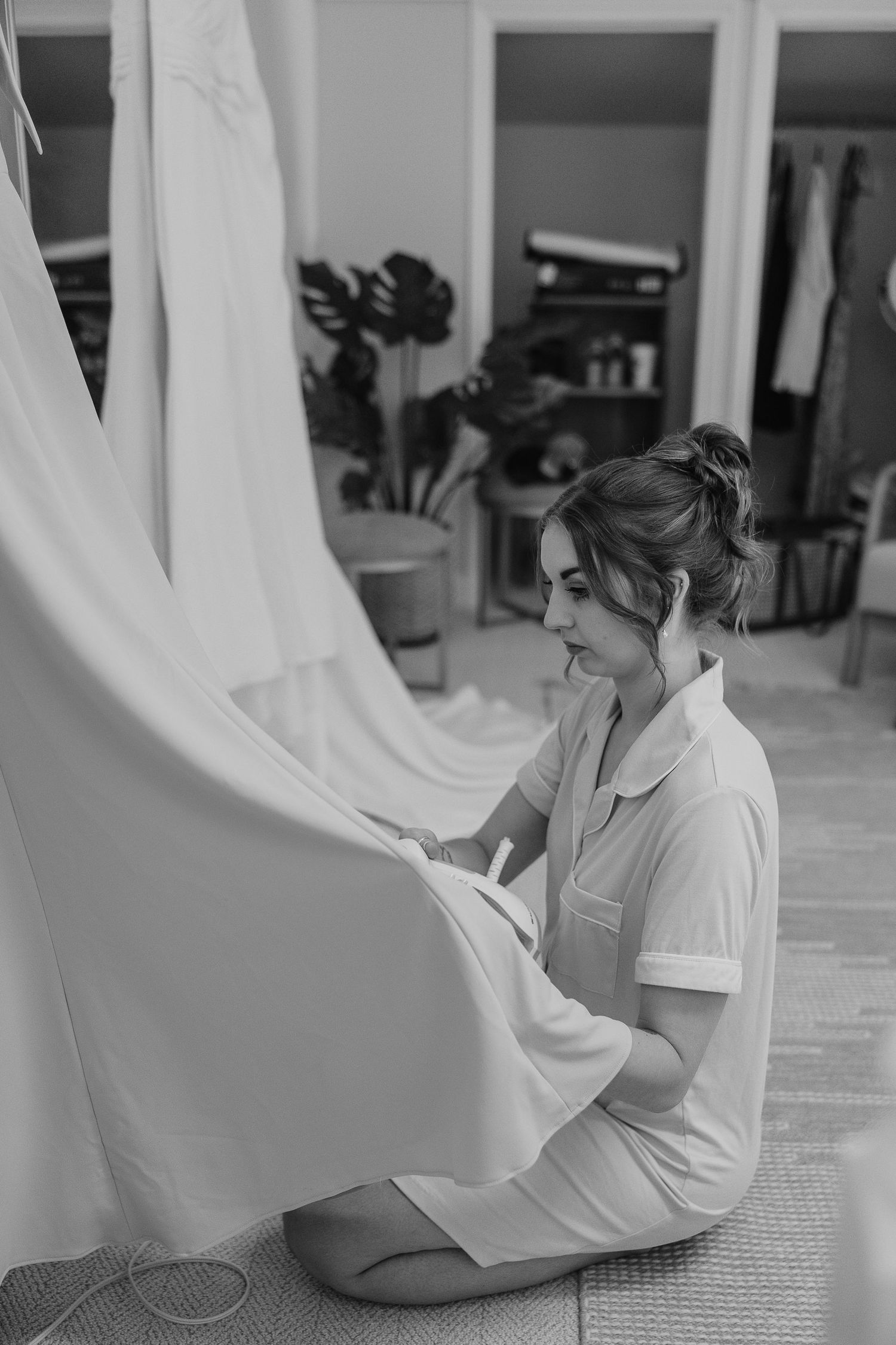 A person in white sits on a floor with flowing white fabric in a bright interior space.