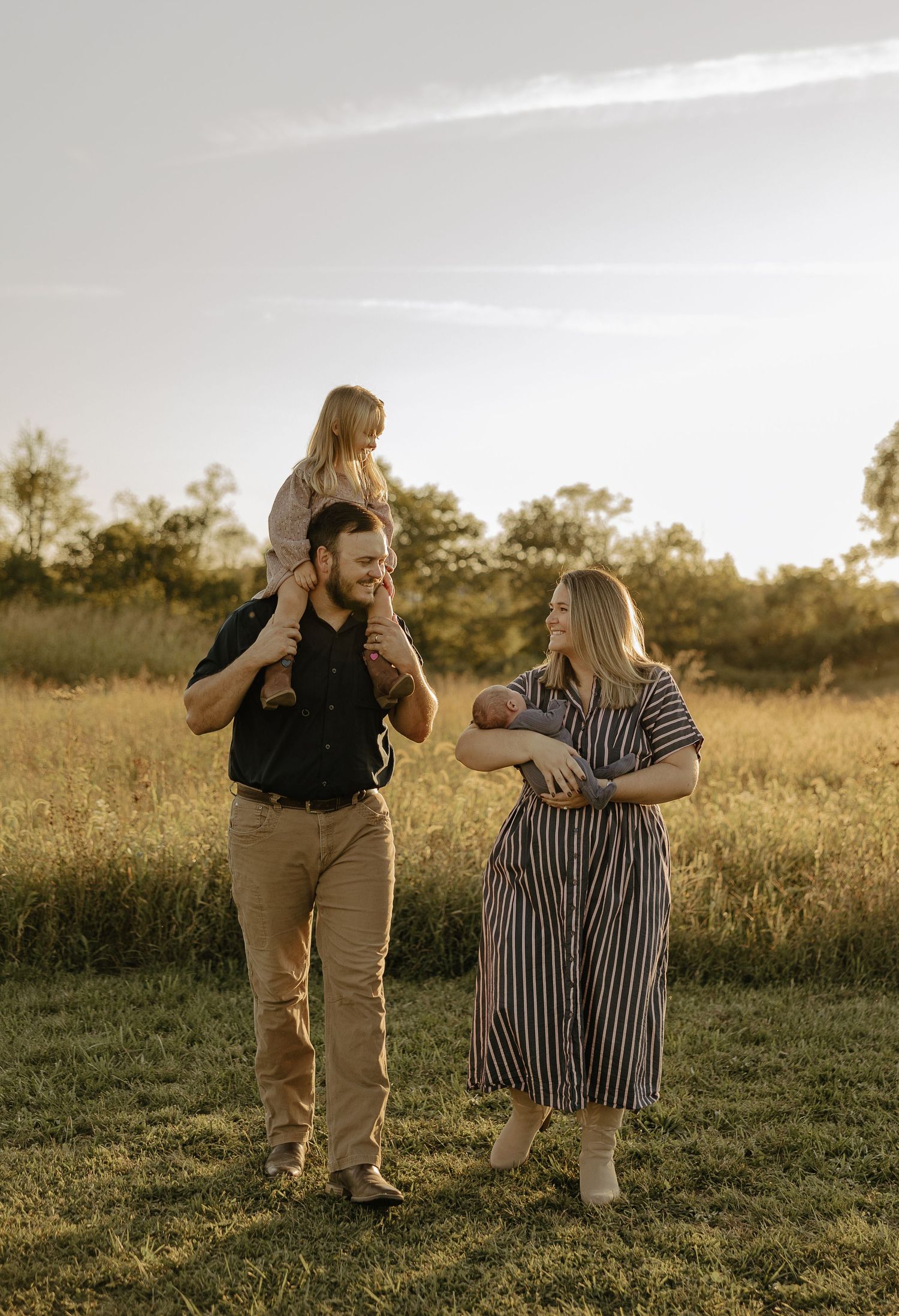 Friends laugh and play together in a golden field during a warm summer evening.