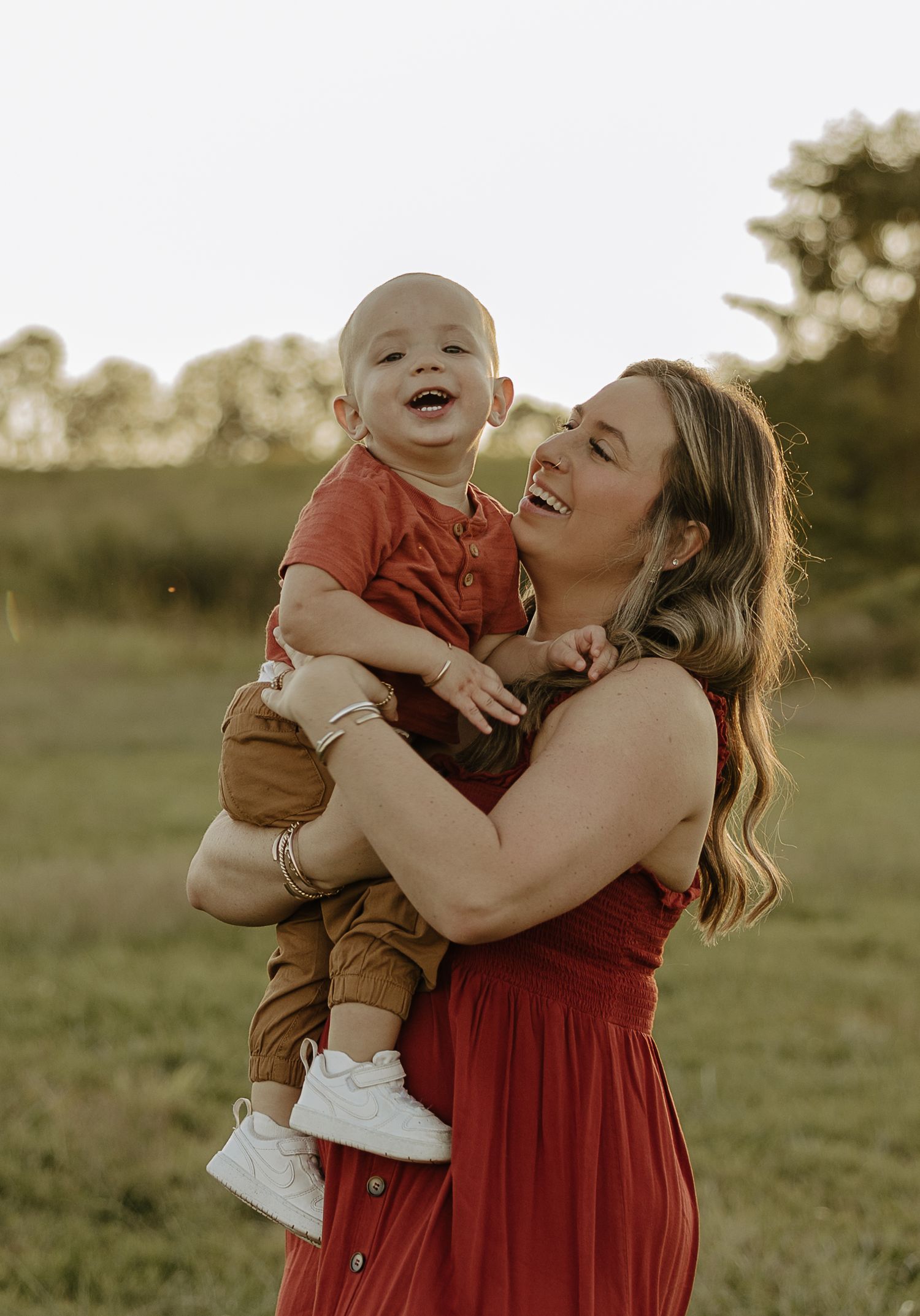 Mother and baby sharing joyful moments in golden evening light.
