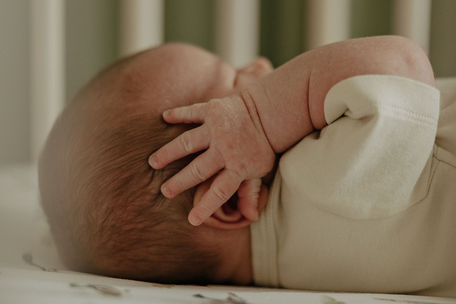 Gentle close-up of a newborn baby's delicate hands in soft lighting.
