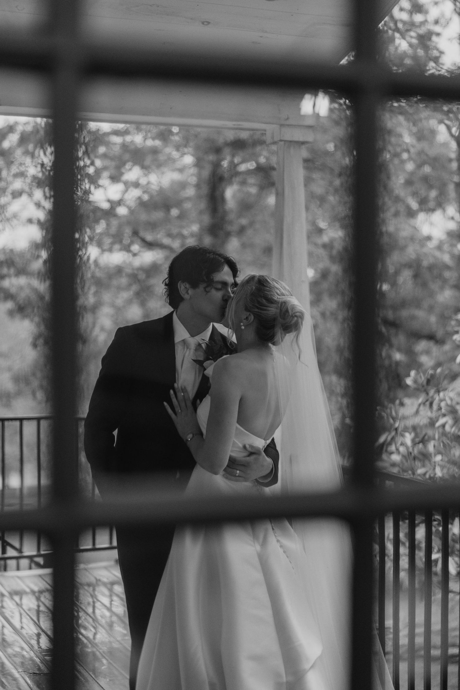Romantic black and white portrait of newlyweds on a covered porch.
