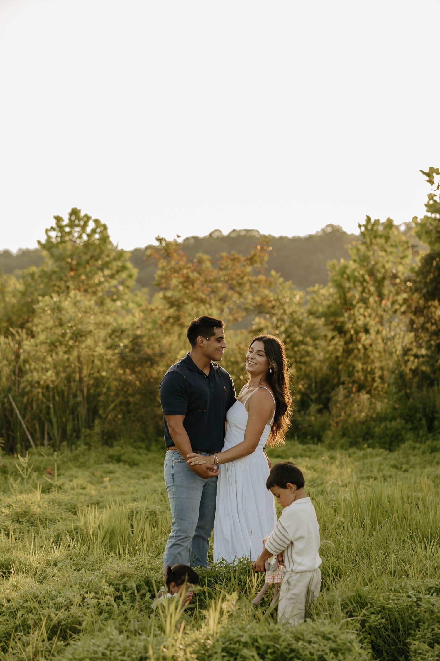 Family sharing intimate moments together in a sunlit meadow.