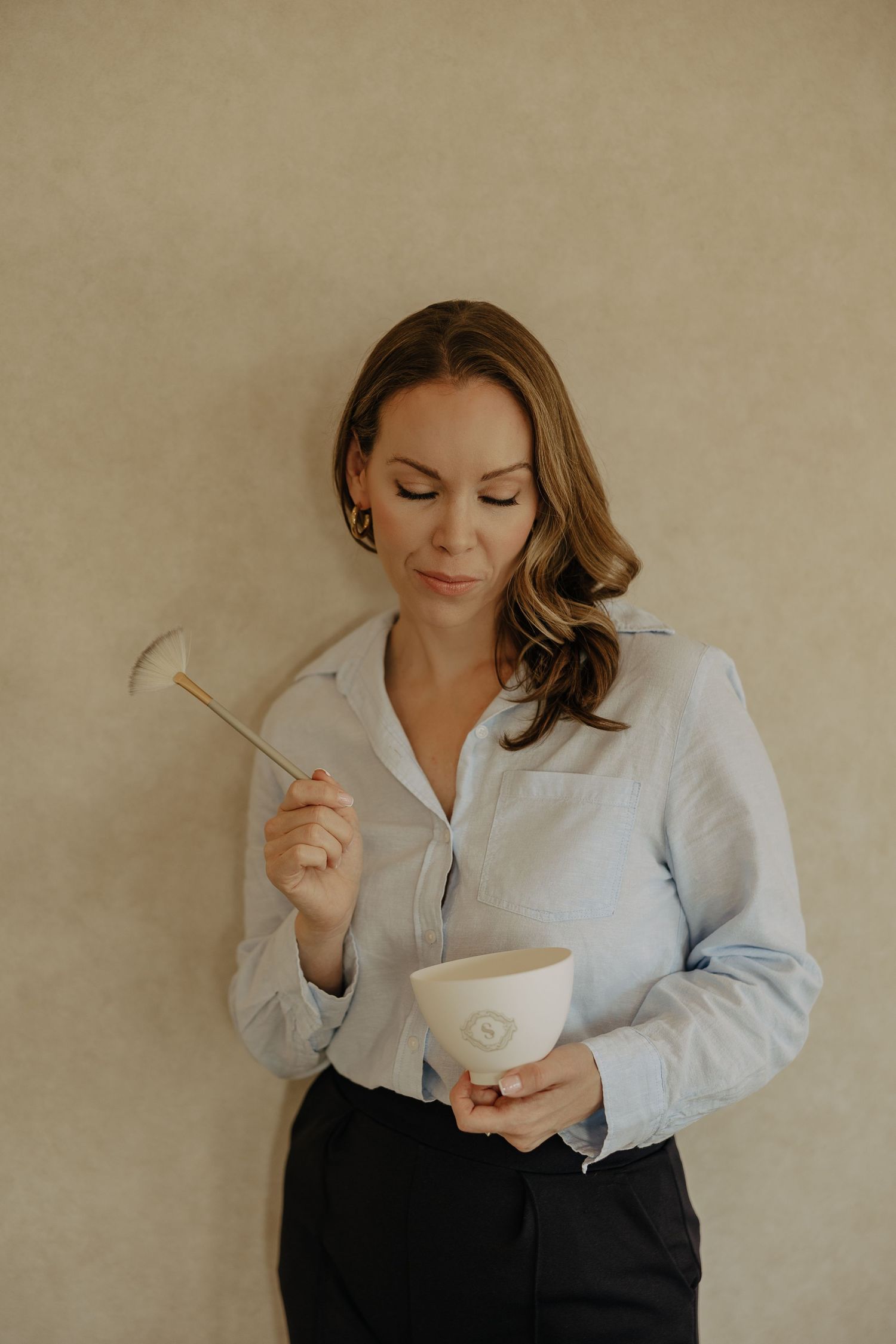 Person in business attire enjoying a warm beverage from a white cup.