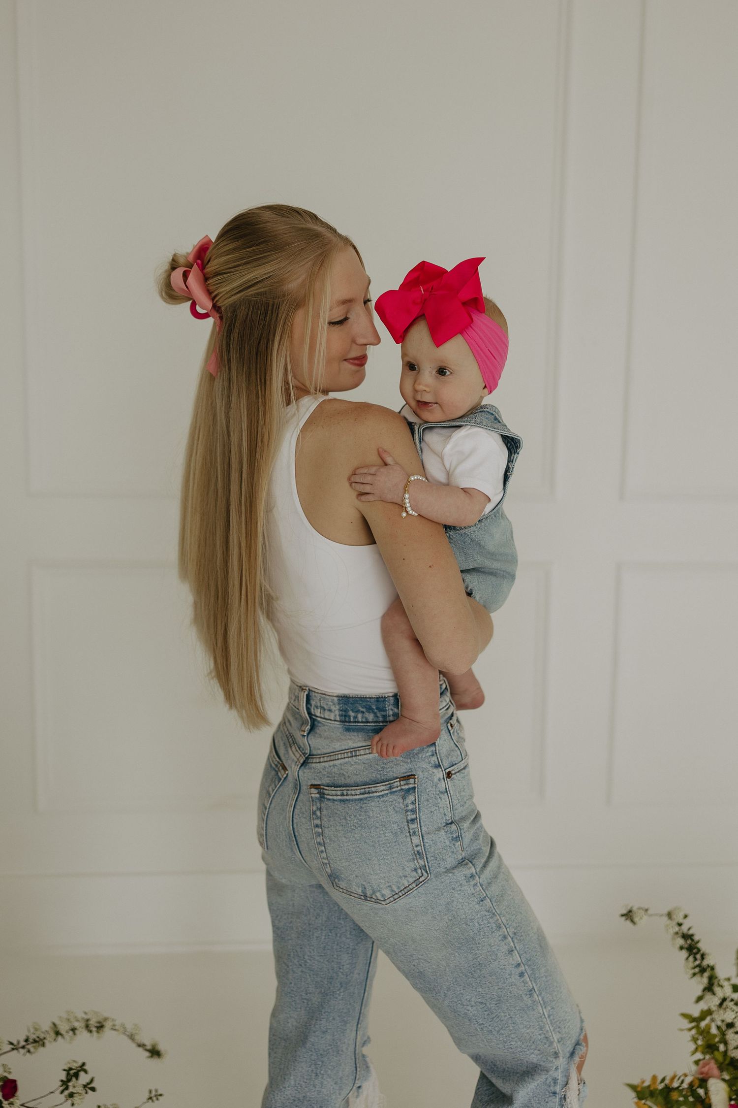 Lifestyle photos featuring light denim and white tops against a minimalist backdrop with flowers.