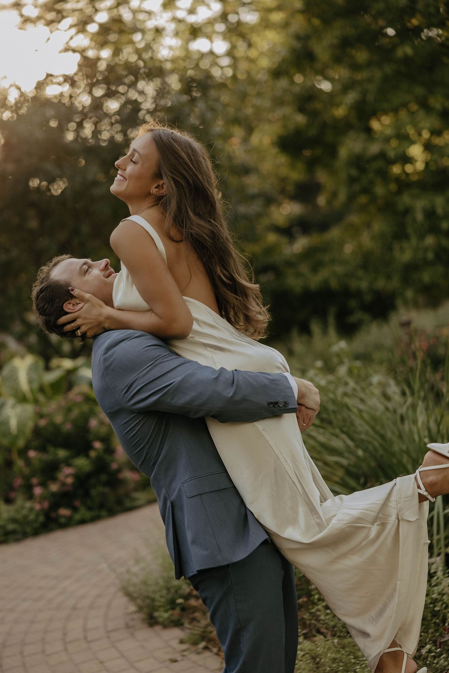 A joyful couple embraces in a garden during golden hour sunset.