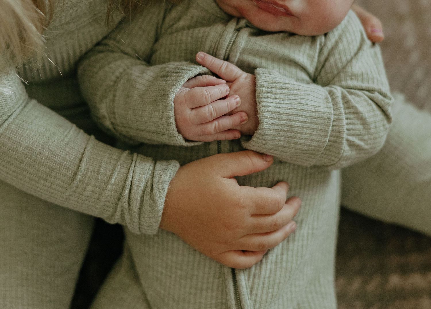 Person wearing a soft sage green sweater shown from torso level.