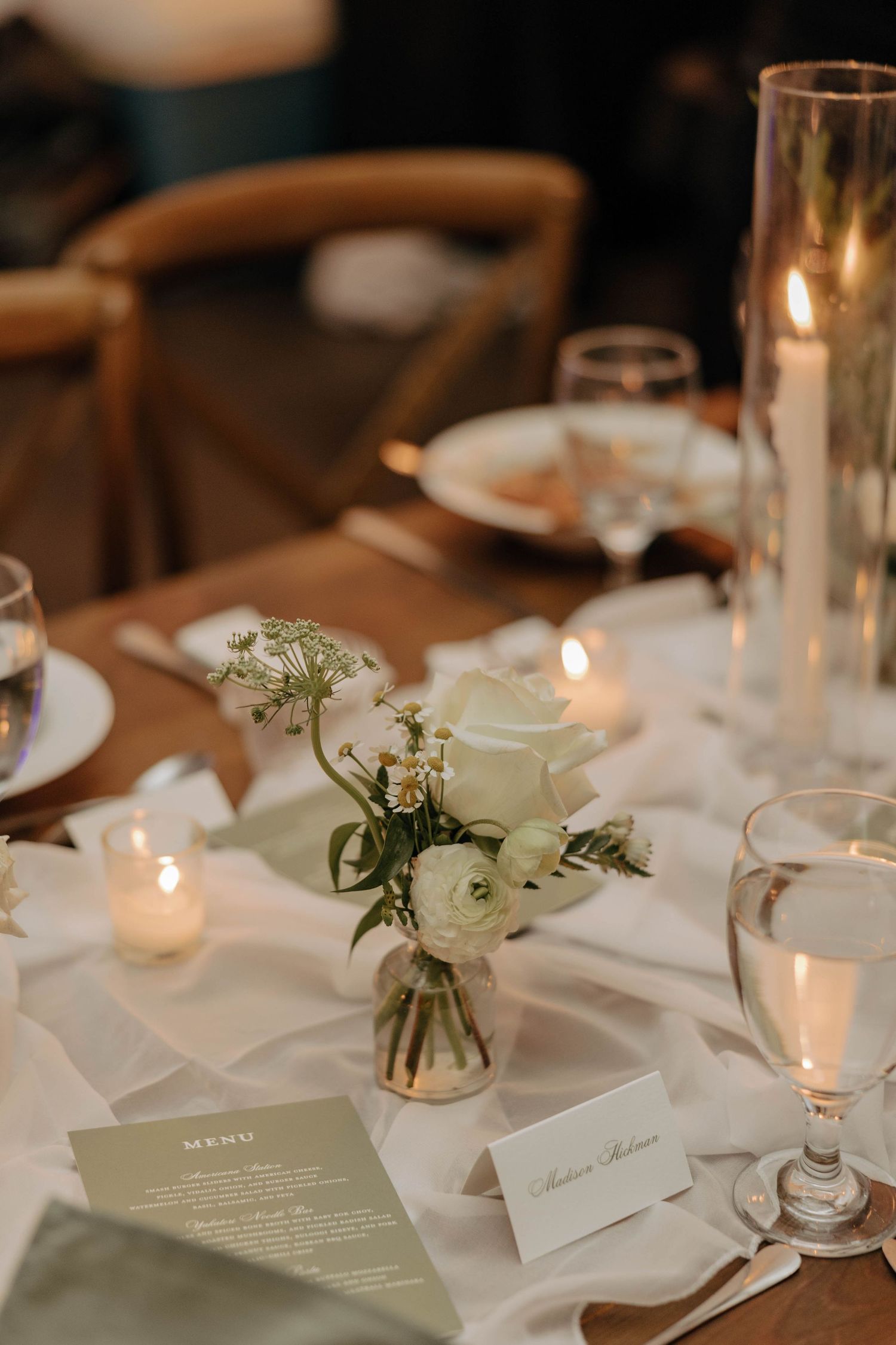 Minimalist wedding reception table setting with white flowers and menu cards.