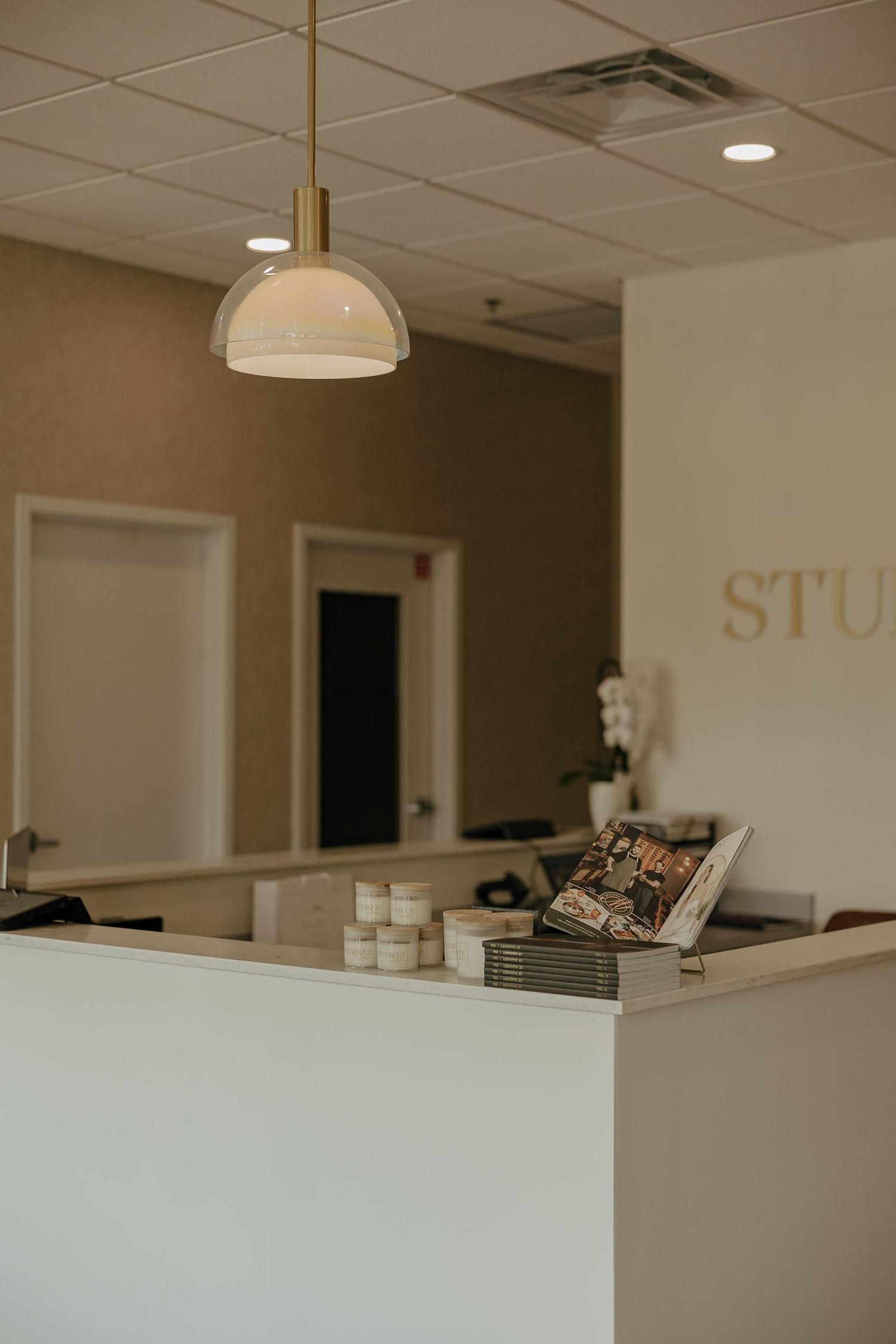 Minimalist spa reception counter with pendant light and product display.
