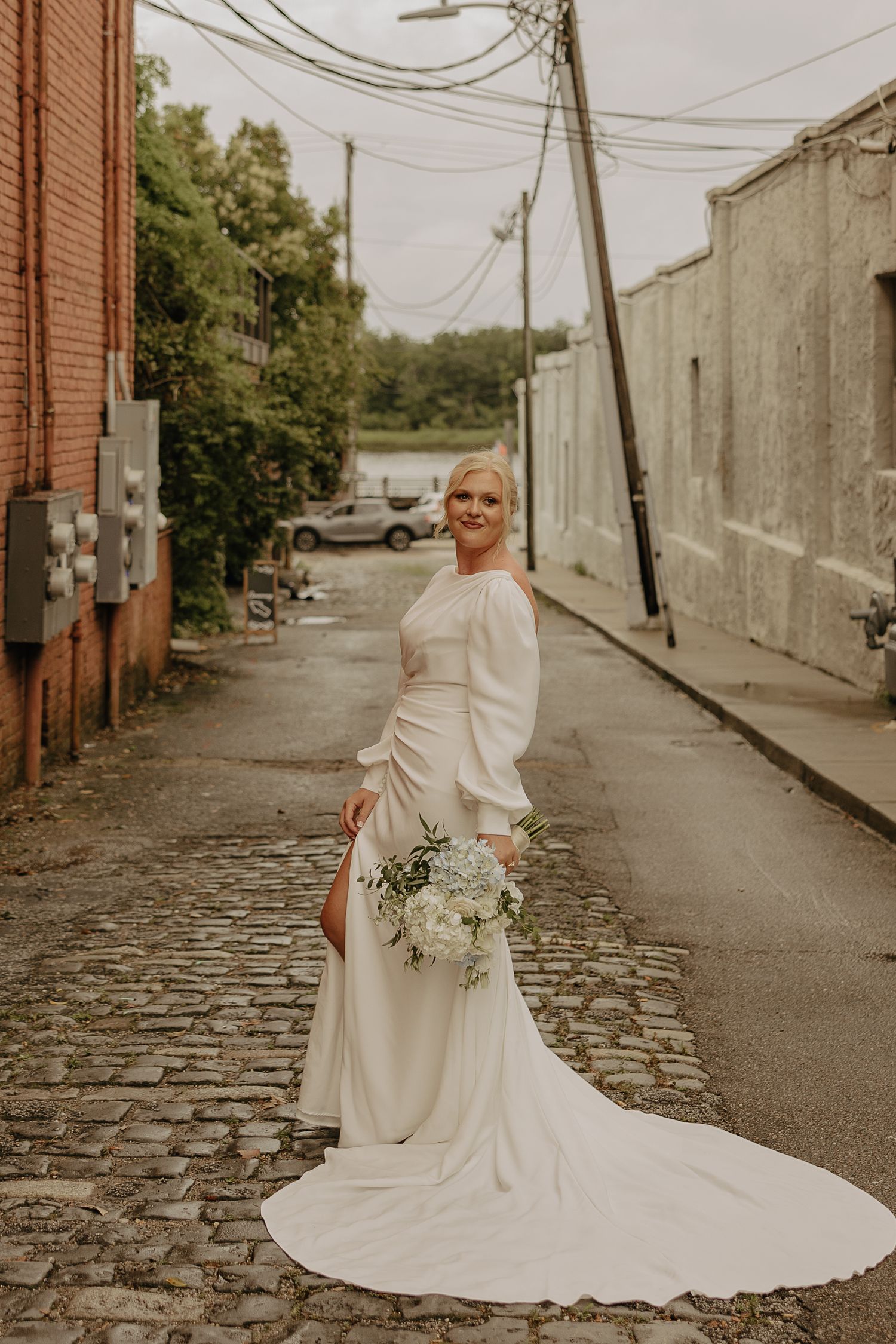 Elegant bridal portraits taken in an urban alley with cobblestone streets and brick buildings.