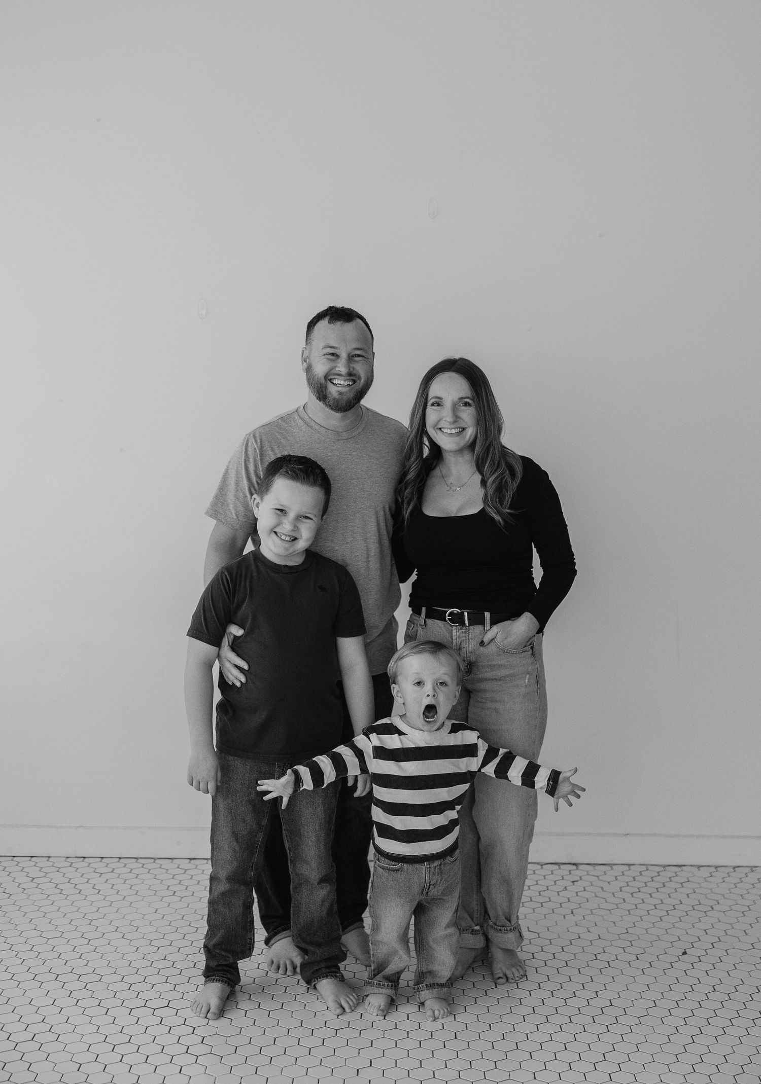 Black and white progressive photos show a family posing against a white wall on carpet.