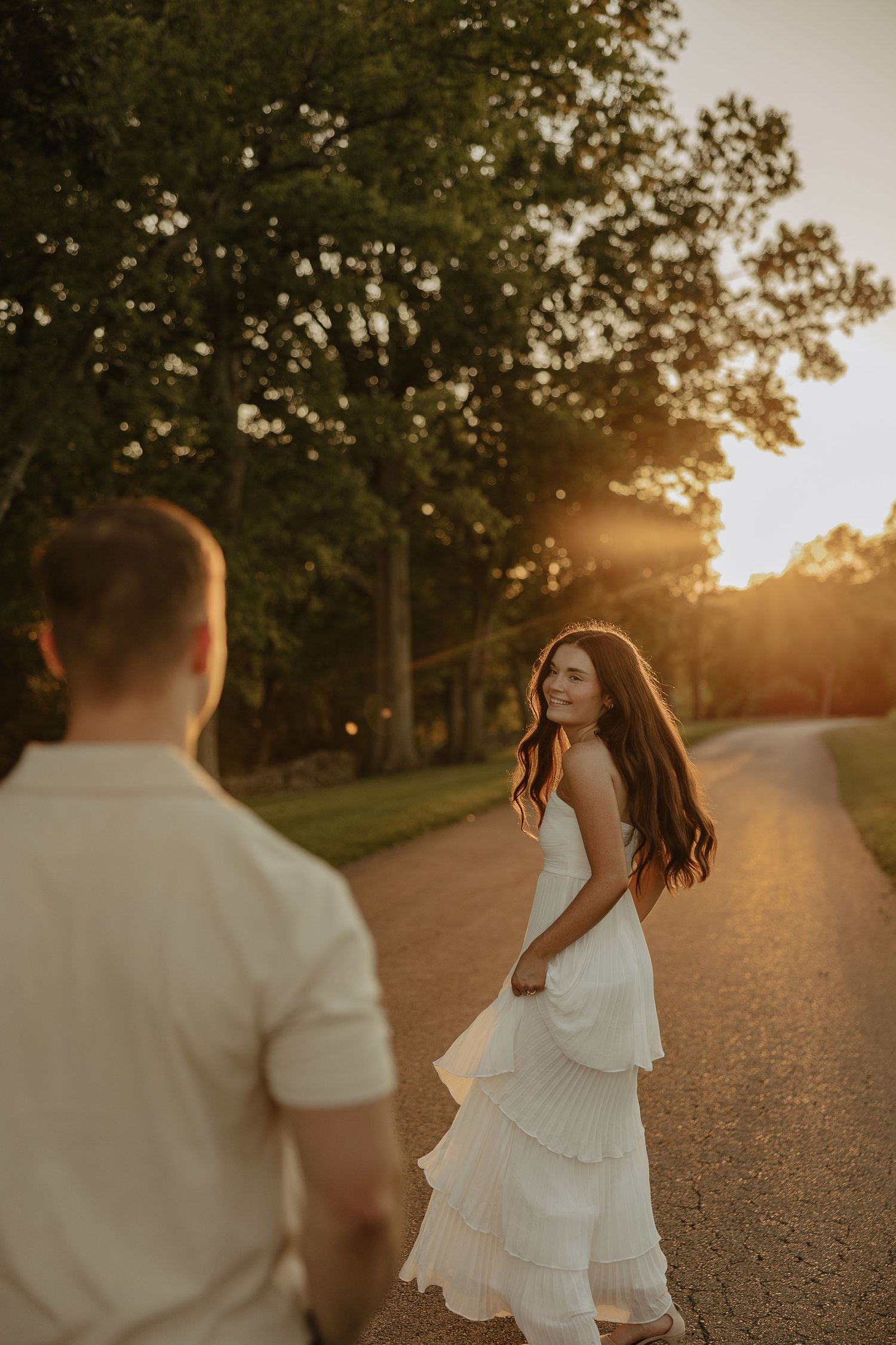 A couple shares candid moments on a sun-drenched path during sunset.