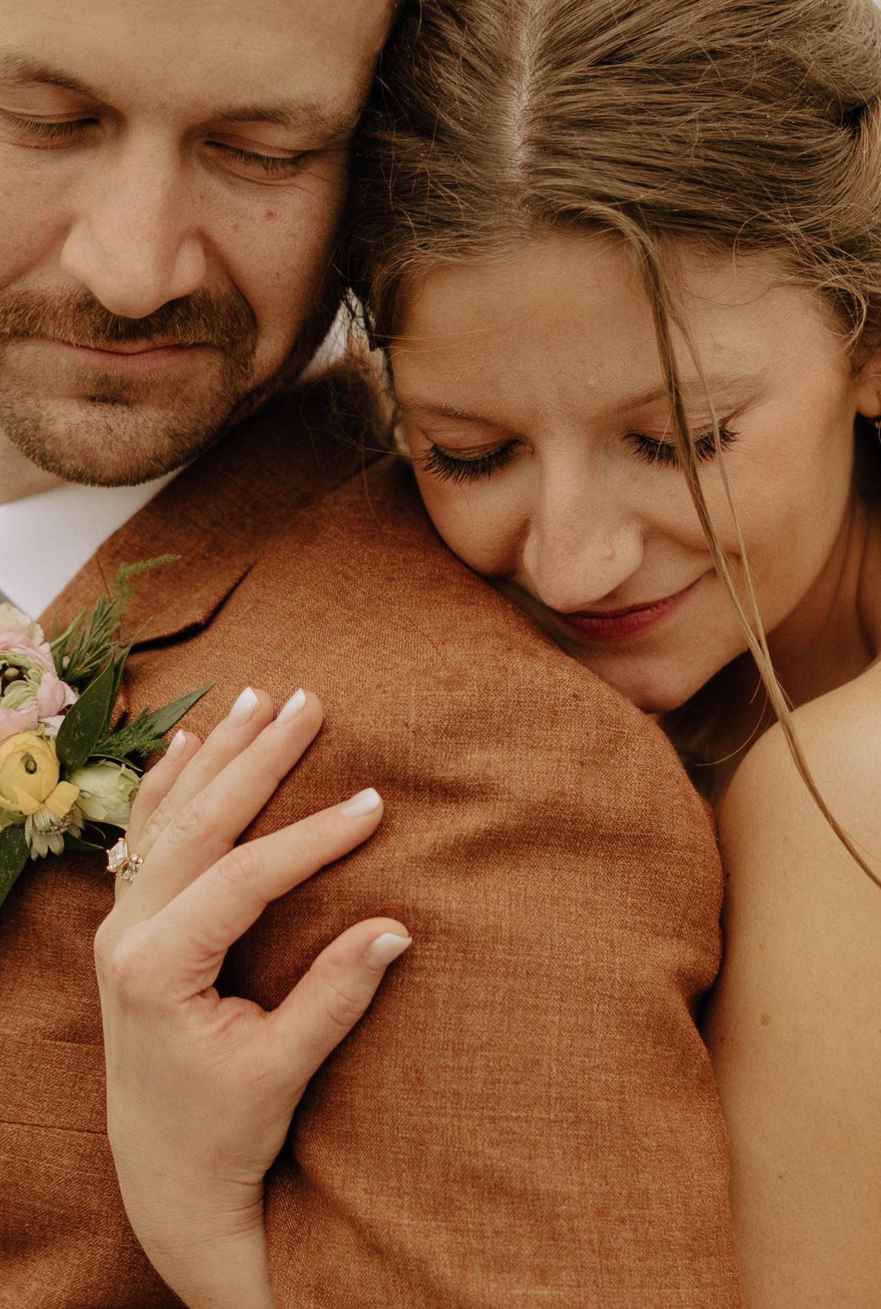Intimate close-up moment between couple in brown and white attire.