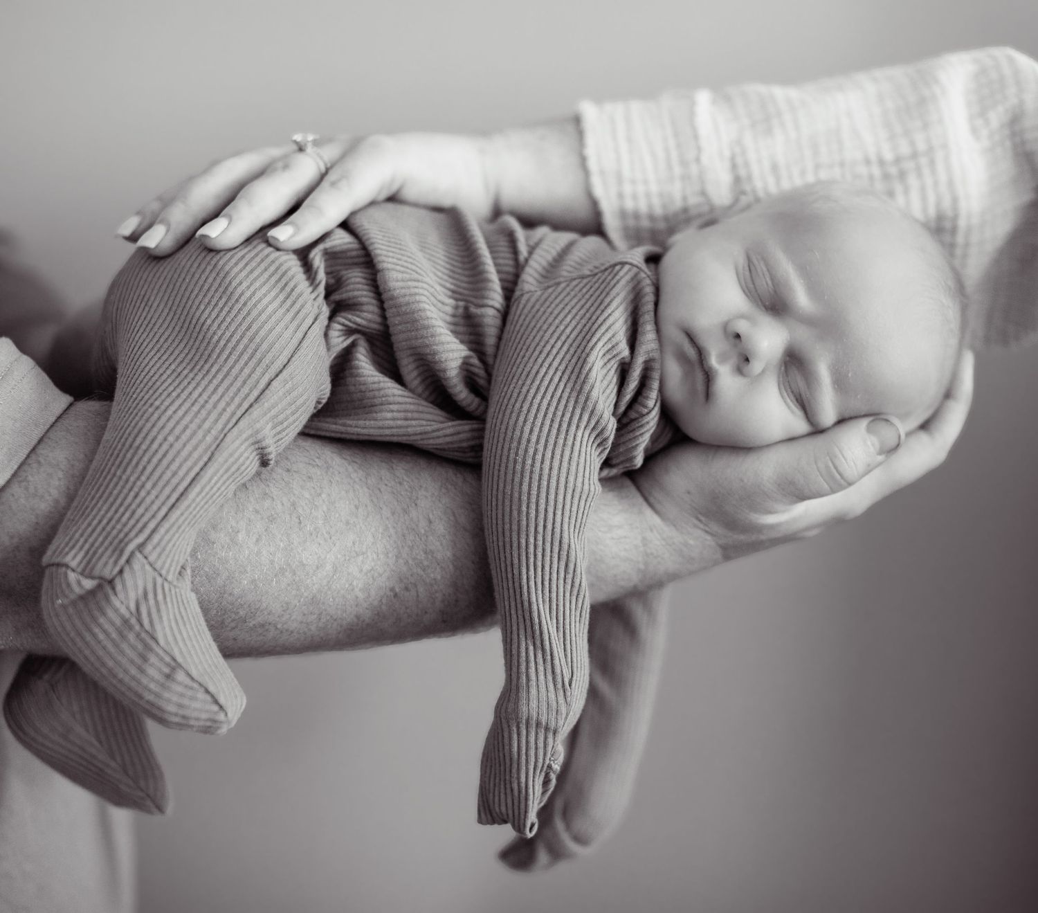A sleeping newborn baby wearing ribbed tights lies peacefully in black and white.