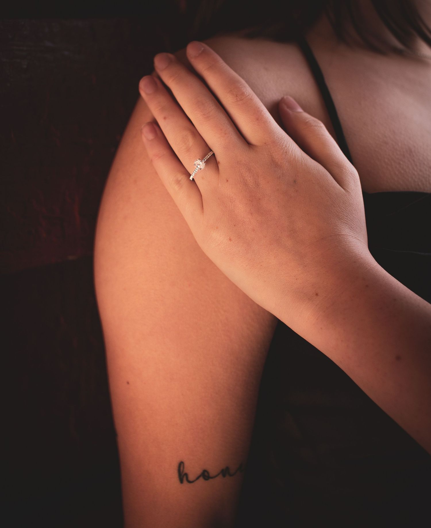 Close-up artistic photo showing hands gently touching bare skin in dramatic lighting.