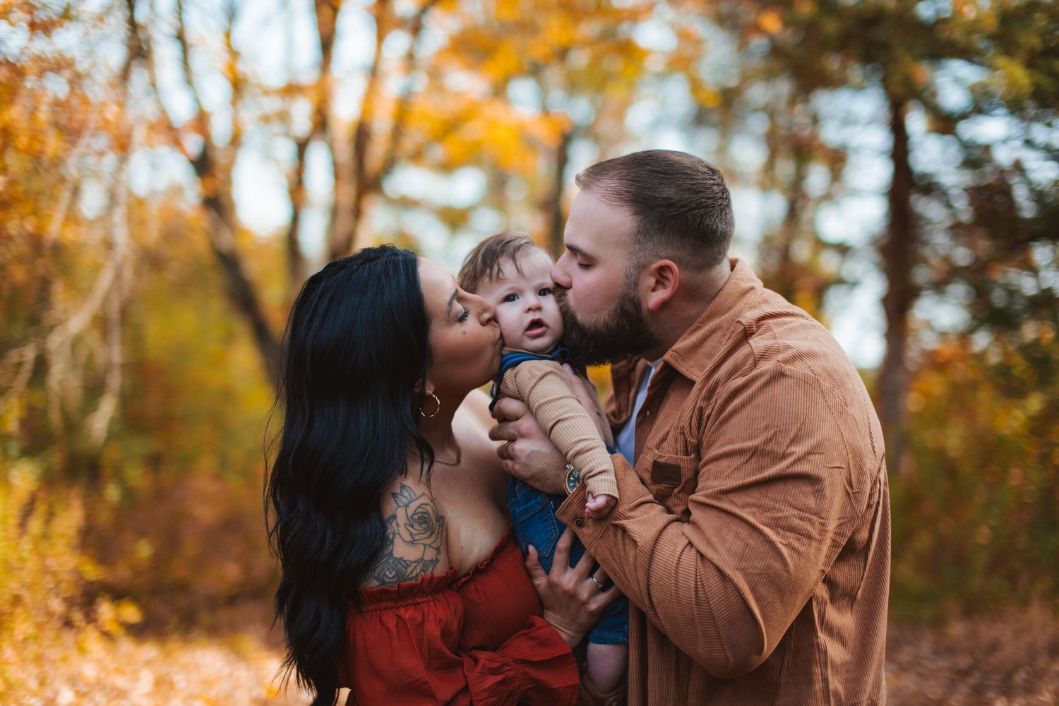 A couple shares romantic moments in a vibrant autumn forest setting with golden leaves in the background.