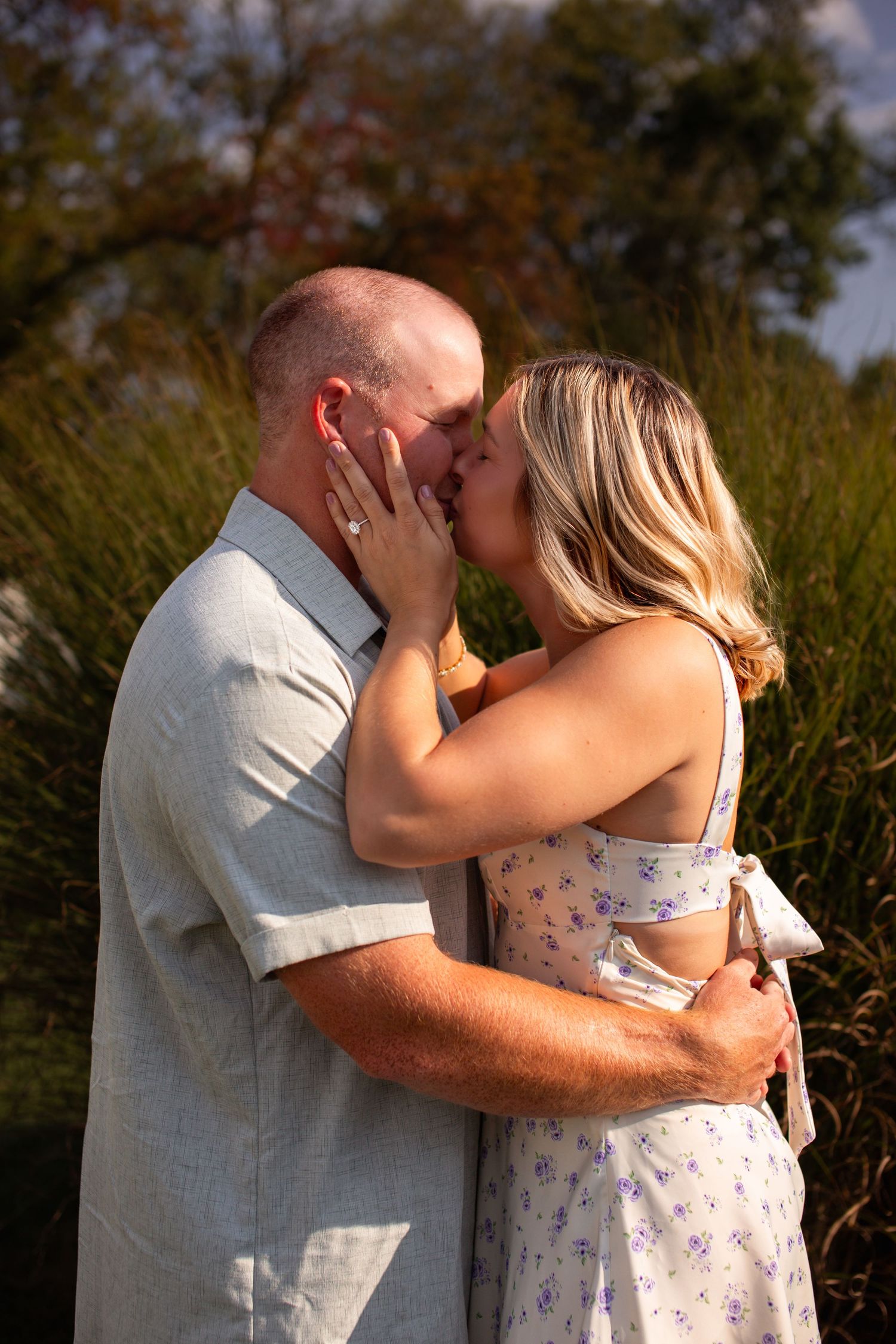 A romantic moment captured between a couple in a field during golden hour.