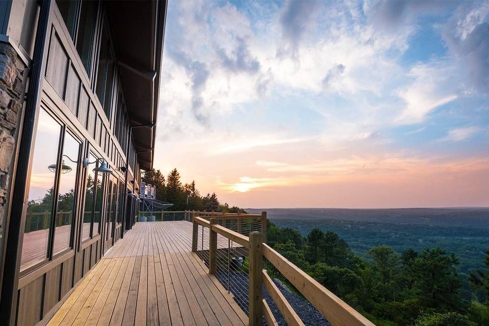 Panoramic view of a mountain landscape with wooden deck railing at sunset.