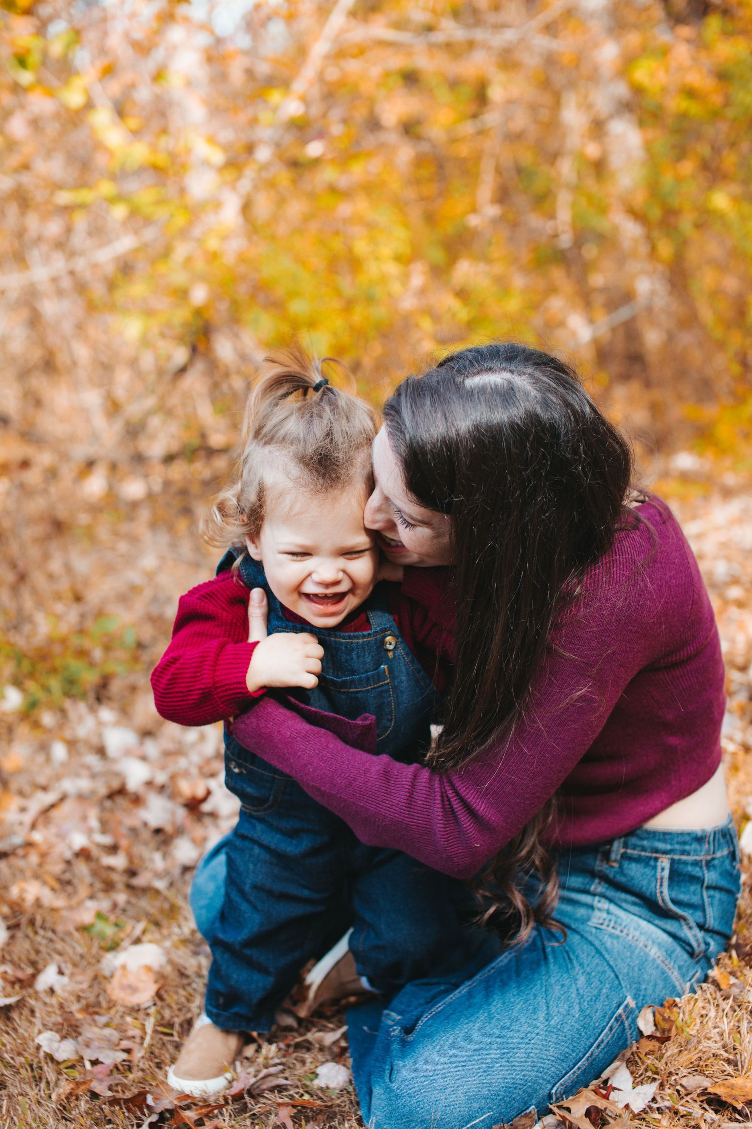 A tender moment captured between parent and child among fallen autumn leaves.