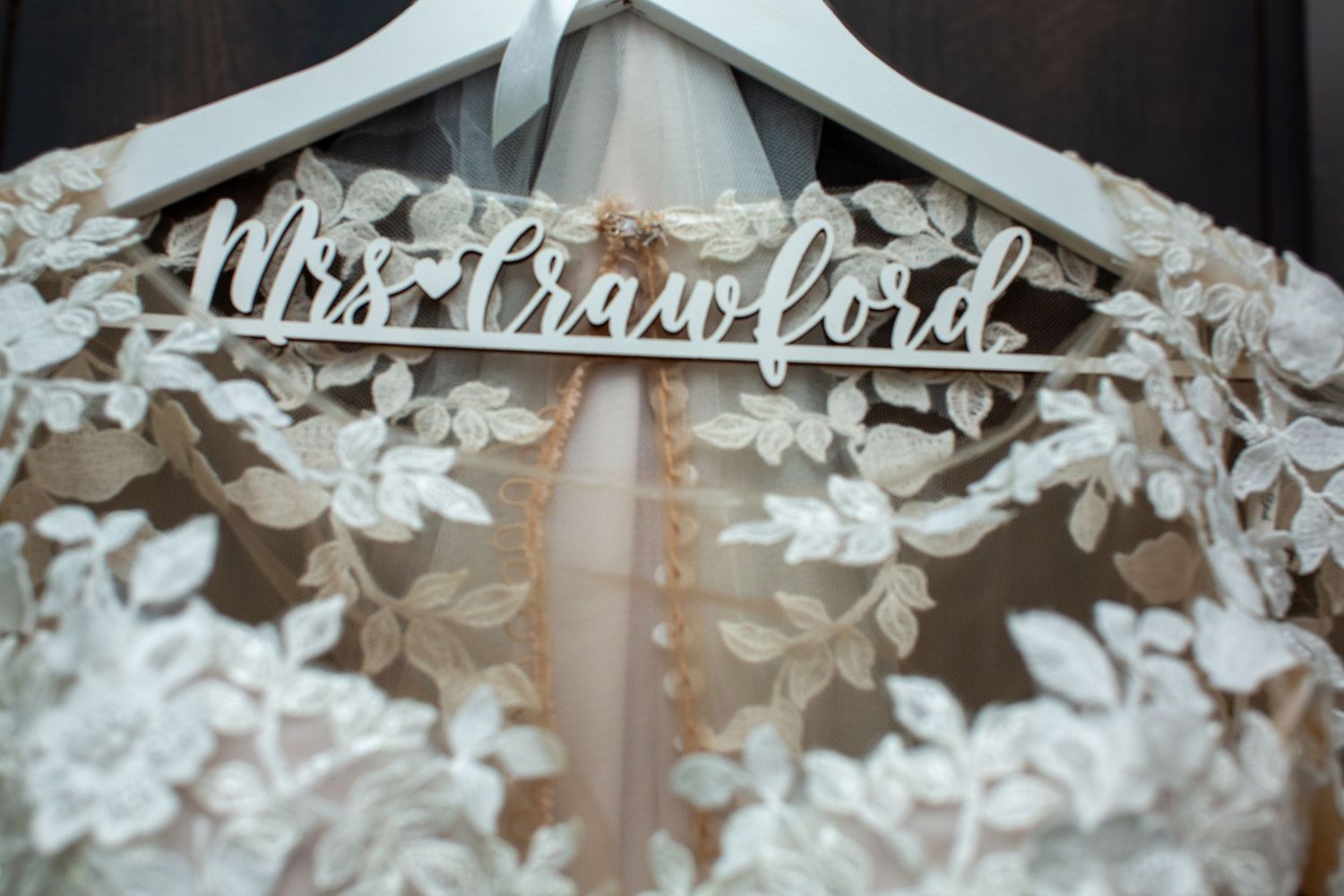 Detailed view of a personalized wedding dress hanger with delicate lace embellishments.