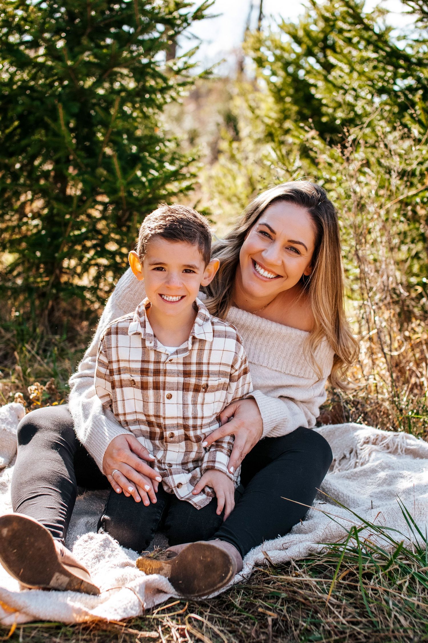 A heartwarming outdoor photoshoot showing tender moments between parent and child on a blanket in nature.