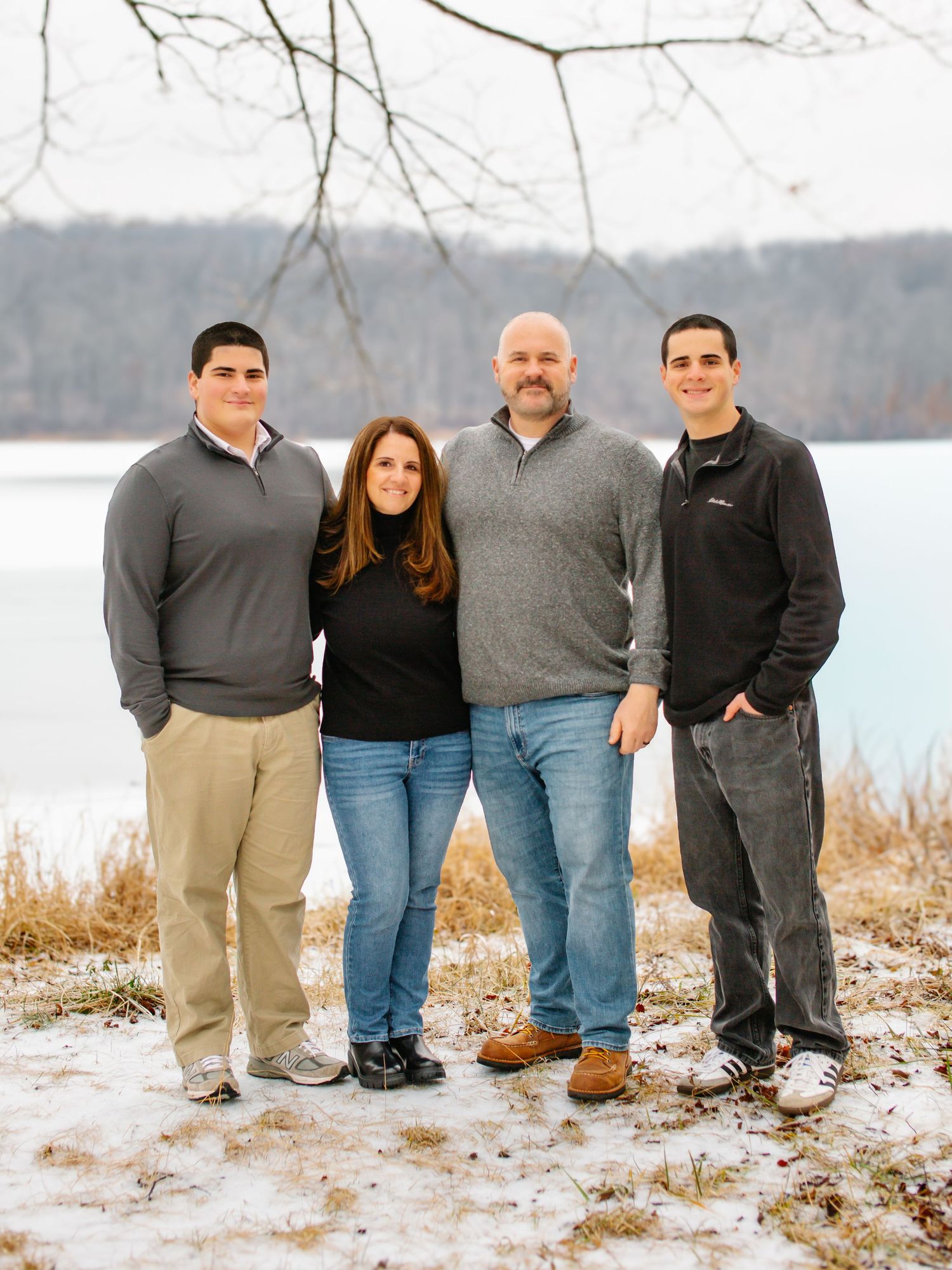 A sequence of five photos showing people posing in winter snow by a lake with bare trees in the background.