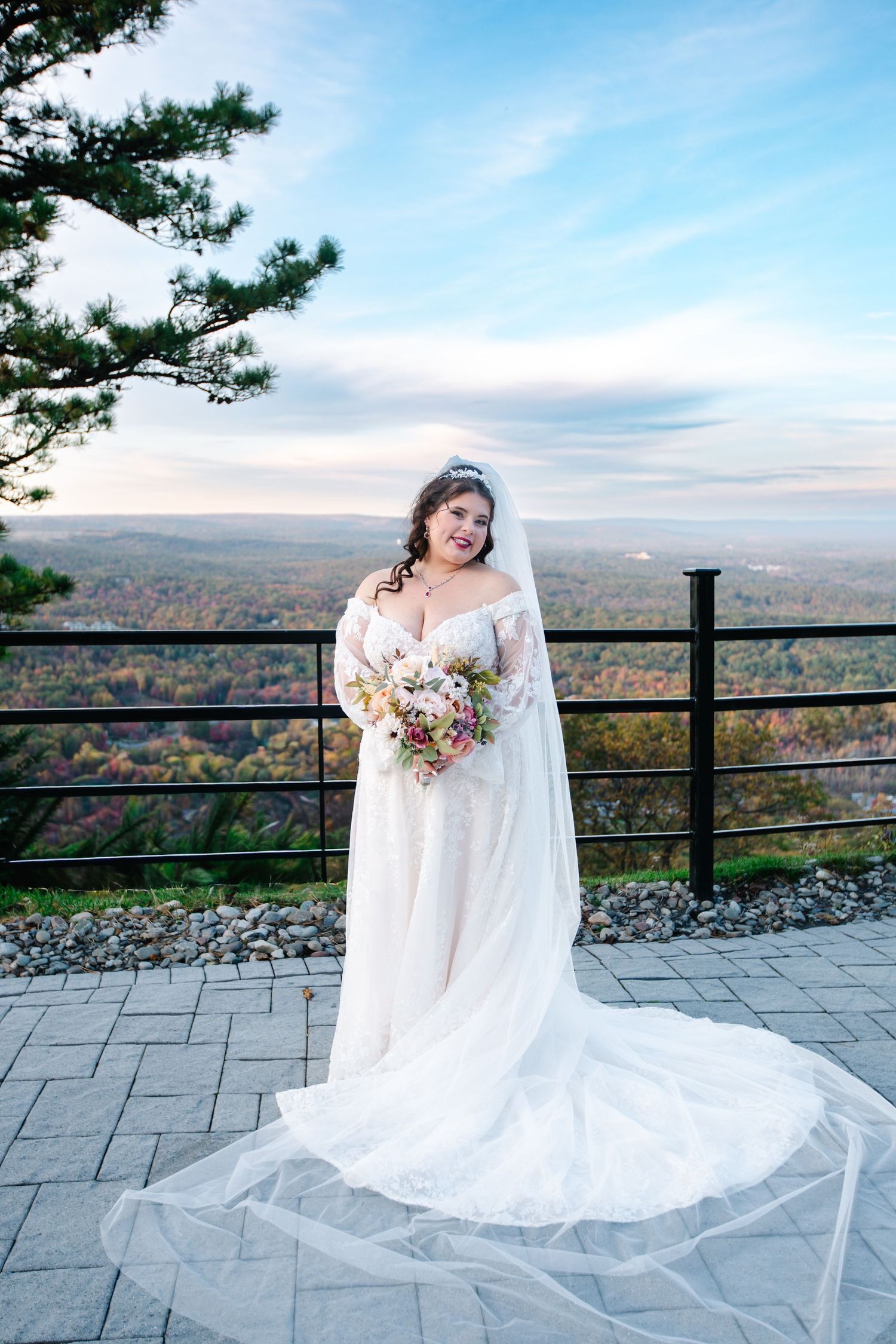 A wedding dress flowing elegantly on a scenic mountain overlook with autumn foliage in the background.