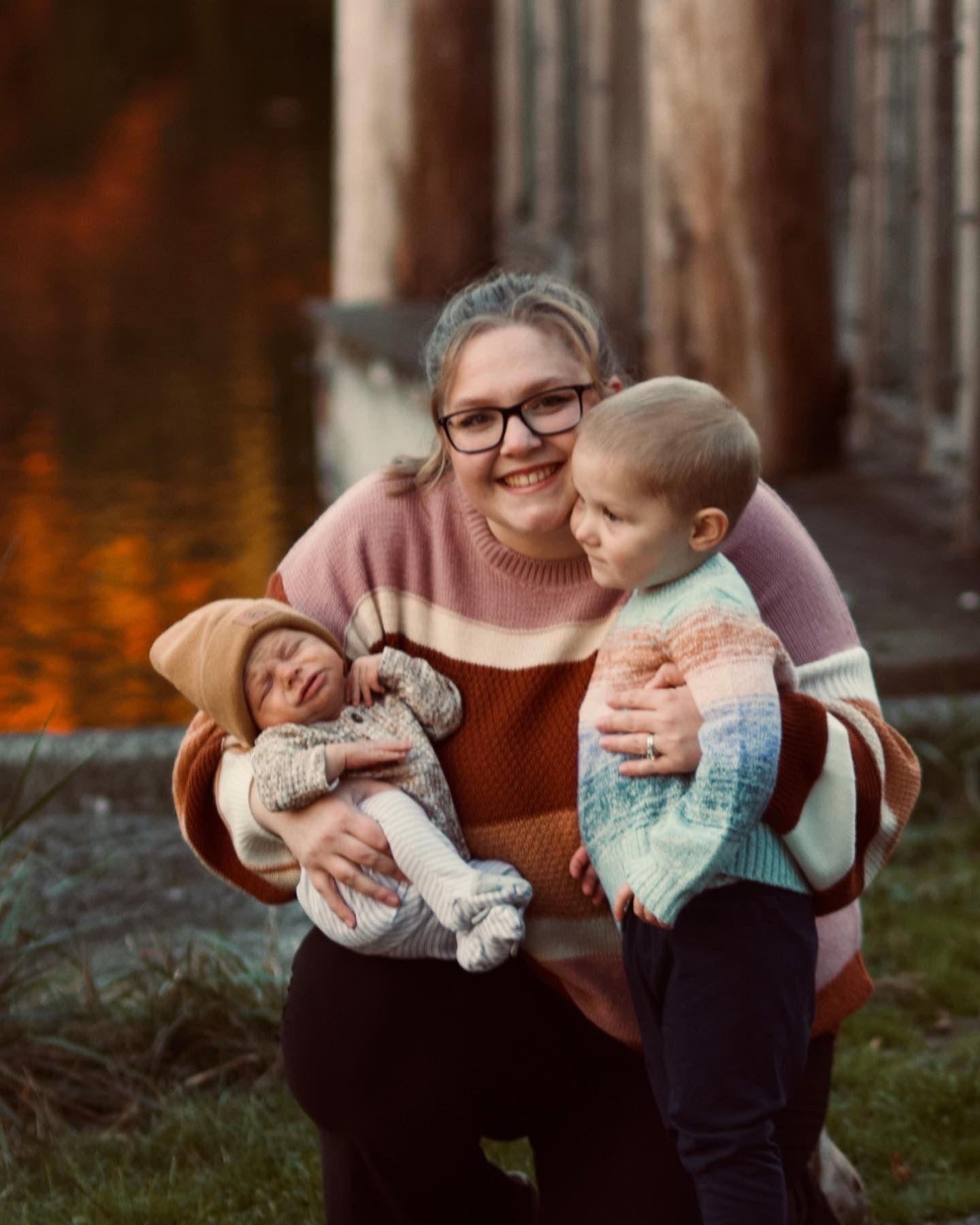 Parent and child sharing playful cuddles and laughter in an outdoor setting at sunset.