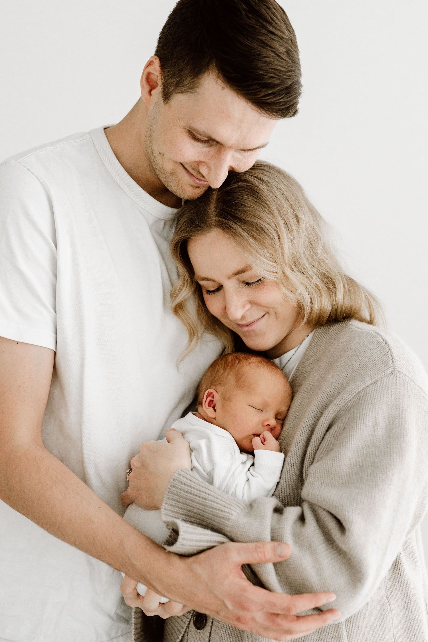 Vastasyntyneen kuvaus studiolla Espoossa ja Helsingissä. Vauvakuvaus, perhekuvaus tai newbornkuvaus studiolla. Äiti ja isä vauva sylissään.
