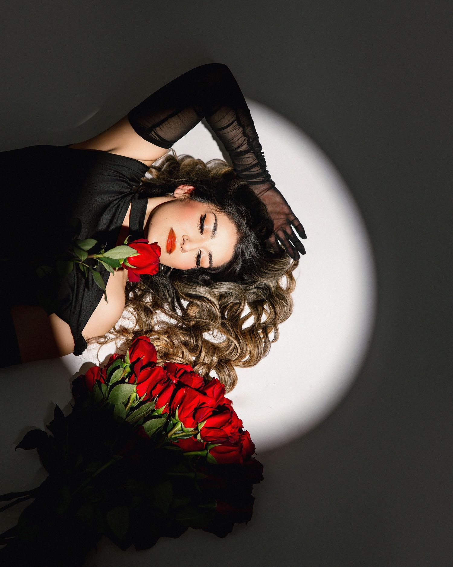 Artistic portrait series with red roses and dramatic lighting showing a person lying down in shadows and highlights.
