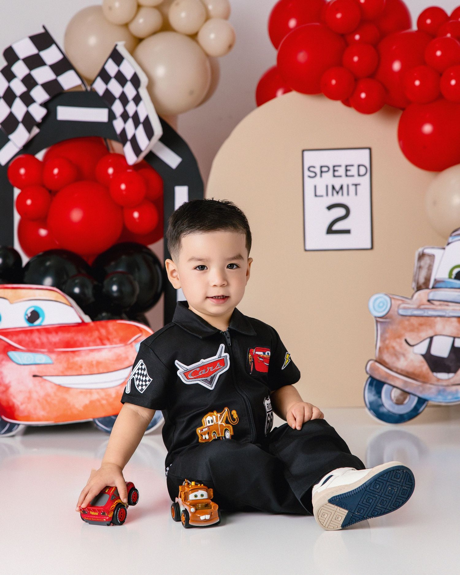 Red and white race car themed birthday party setup with checkered flags and balloon decorations.