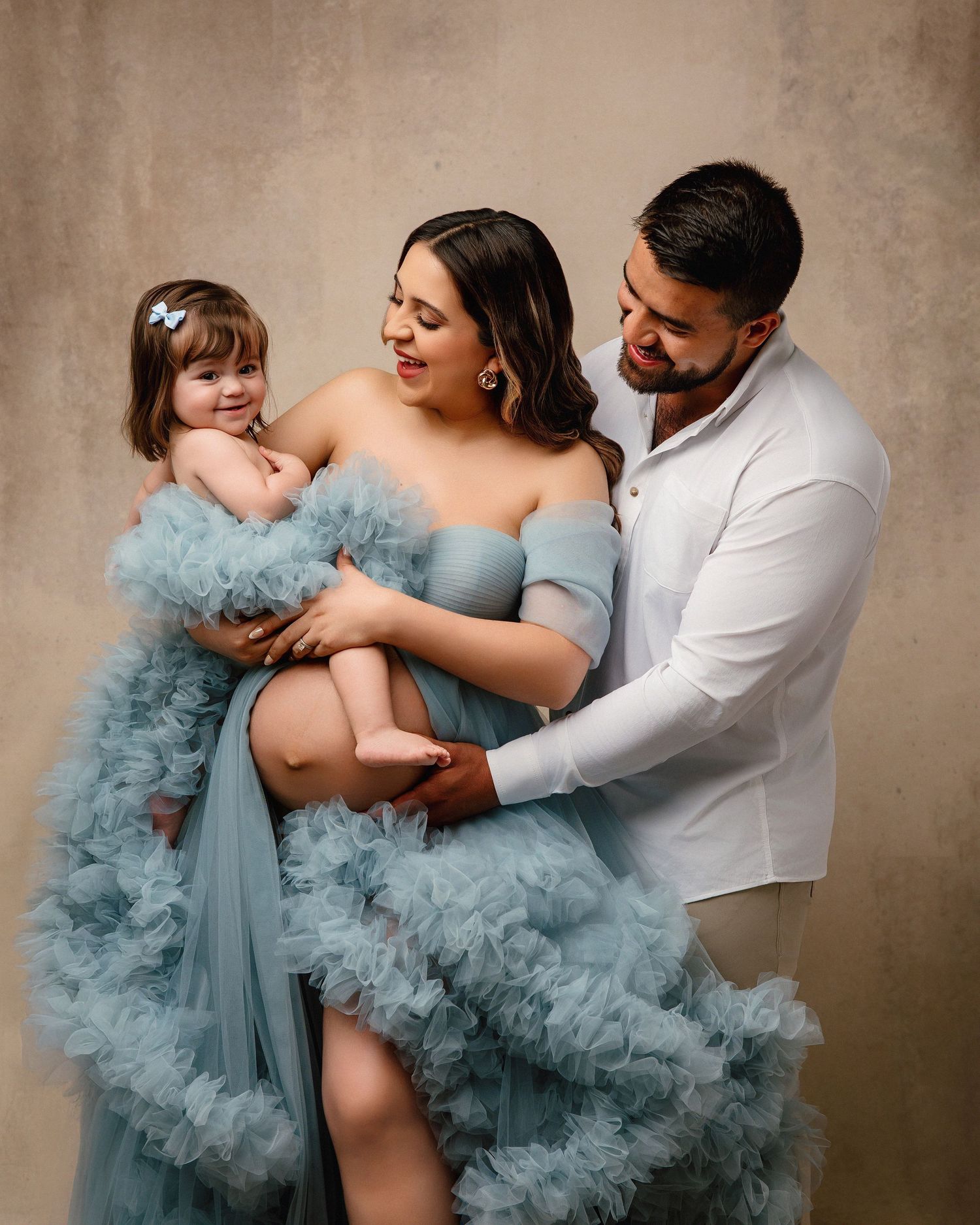 A series of five tender moments showing a family in matching blue and white outfits embracing against a neutral backdrop.