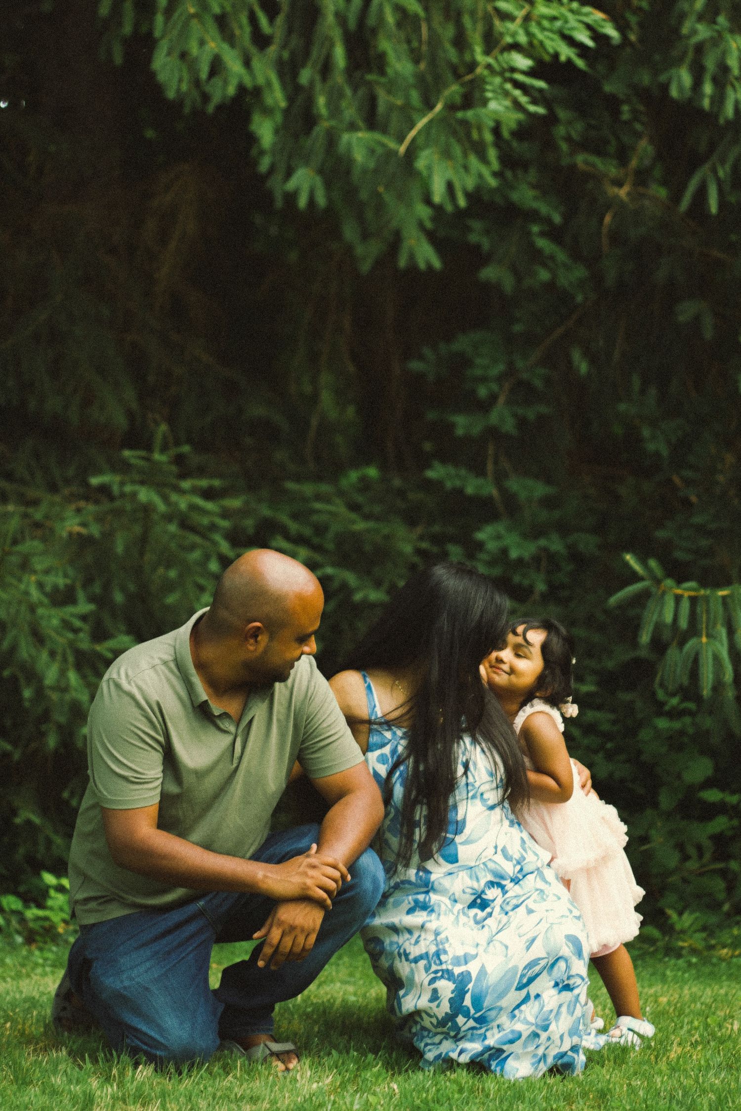 ngton DC, Maryland and Virginia candid family photographer capturing tender moment between family of three in lush green park