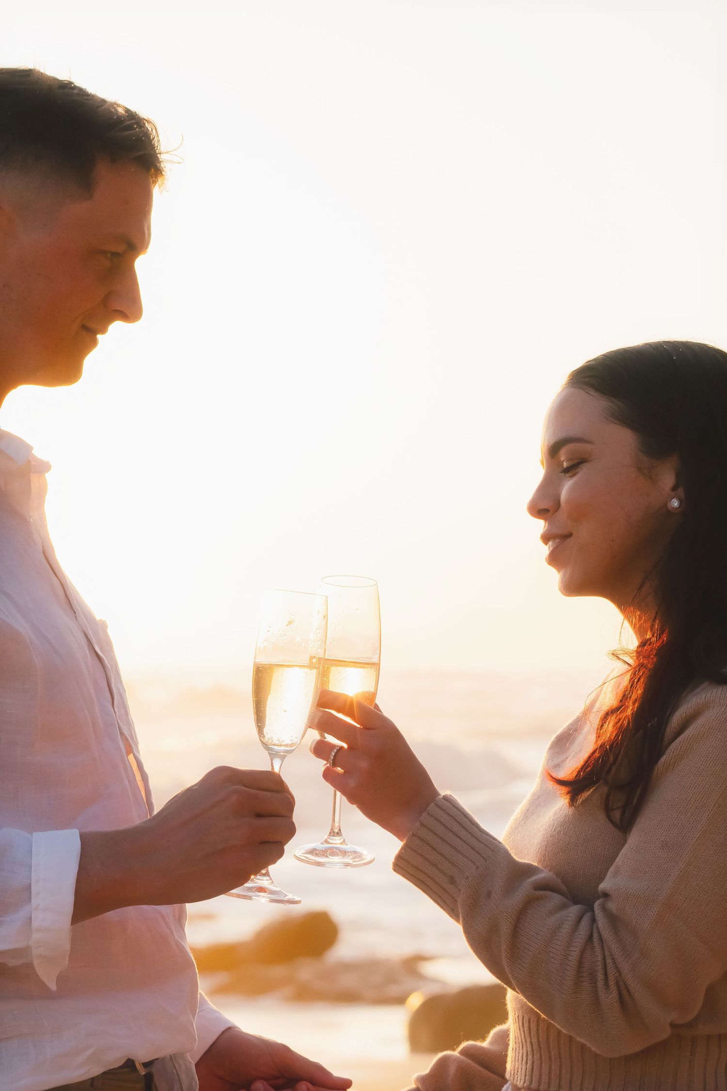 Close-up of a couple toasting with champagne glasses in warm sunset light