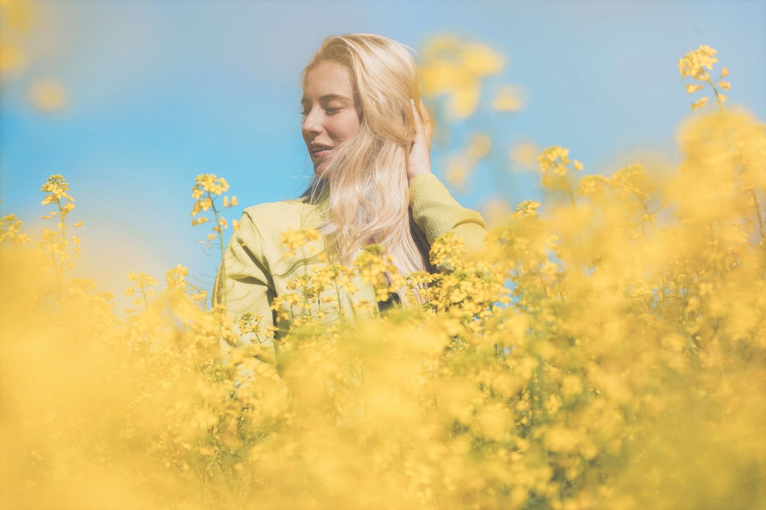 Woman in a lime green shirt in profile, surrounded by canola under a blue sky