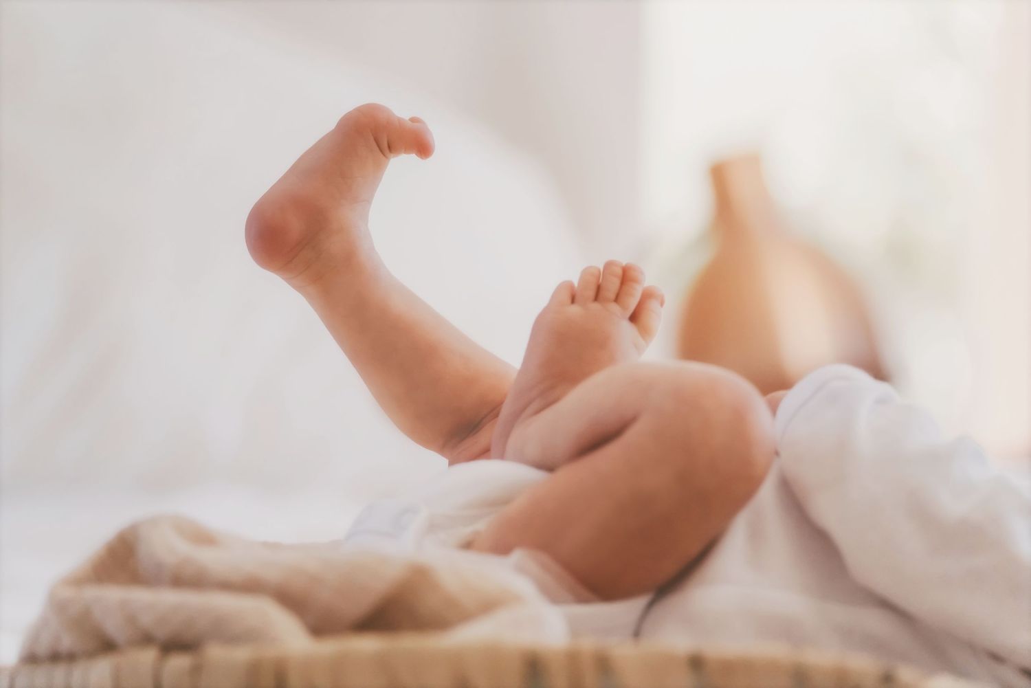 Newborn's tiny legs kicking on a soft blanket in natural light