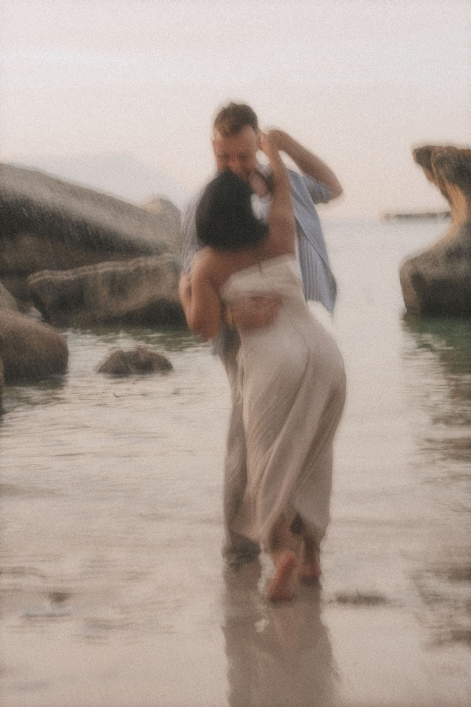 Couple embracing and spinning in shallow water, softly blurred by movement