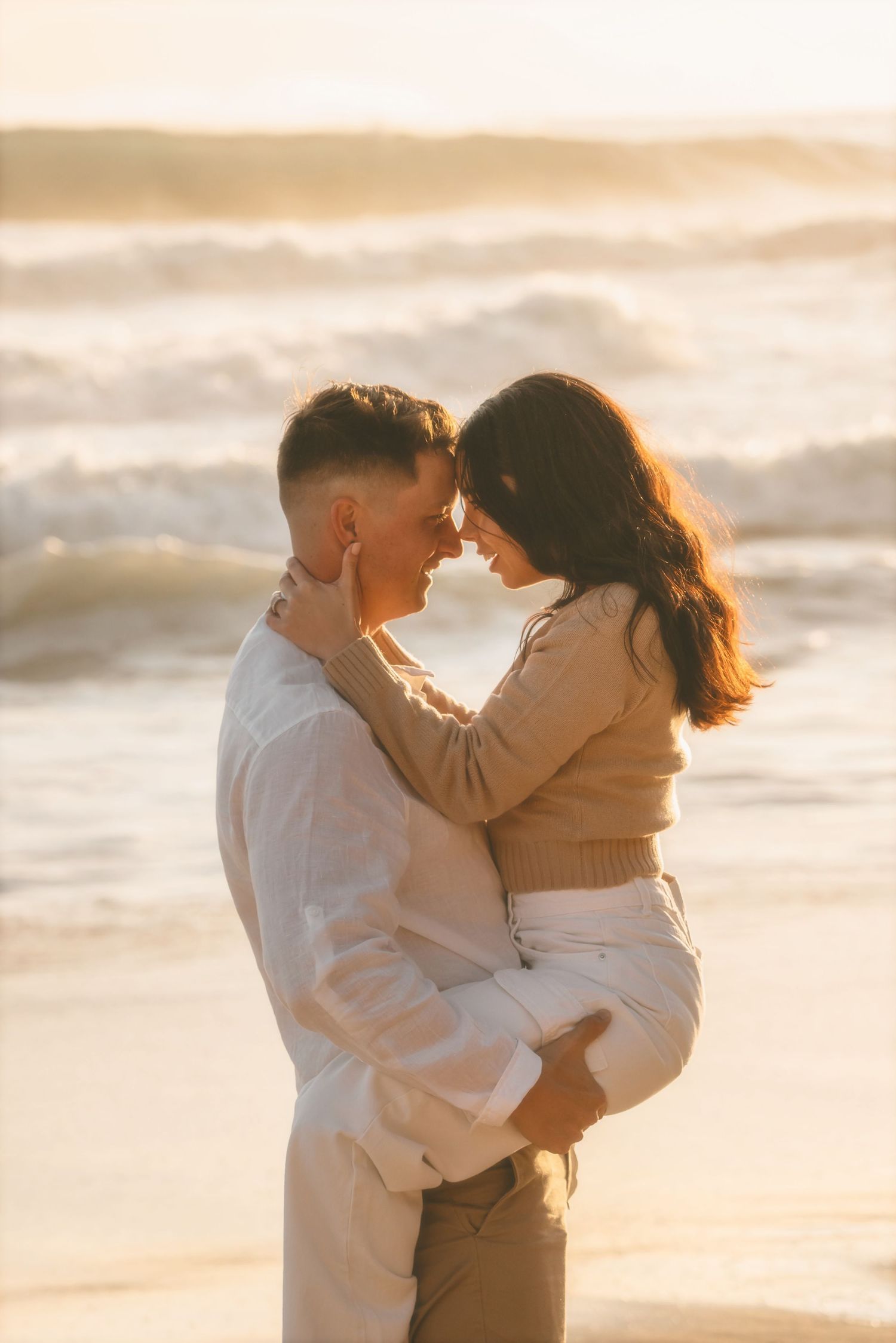 Couple resting their foreheads together in the surf as he holds her close