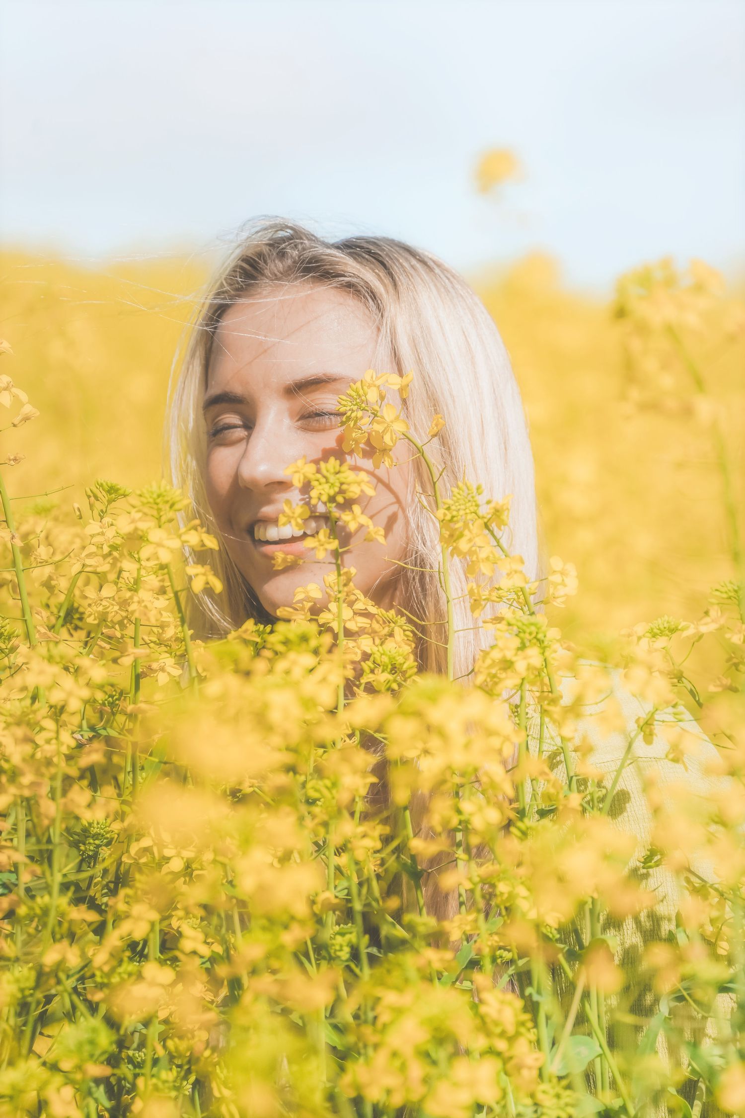 Woman laughing among yellow canola flowers